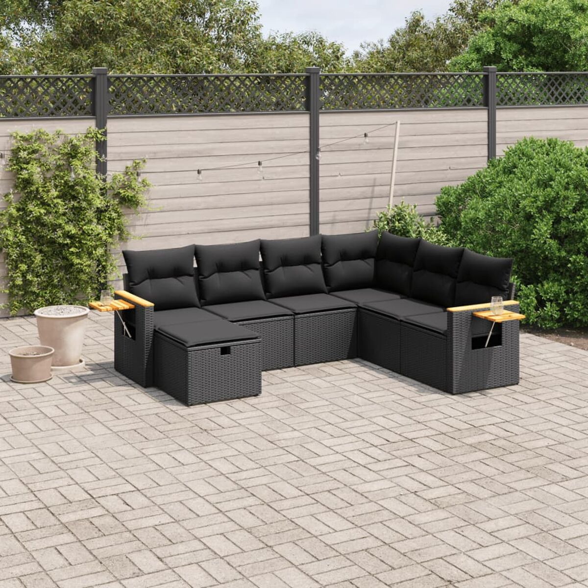 Schwarzes Outdoor-Sofaset aus Korbgeflecht mit schwarzen Kissen, Holzarmlehnen und Beistelltischen auf Terrasse.