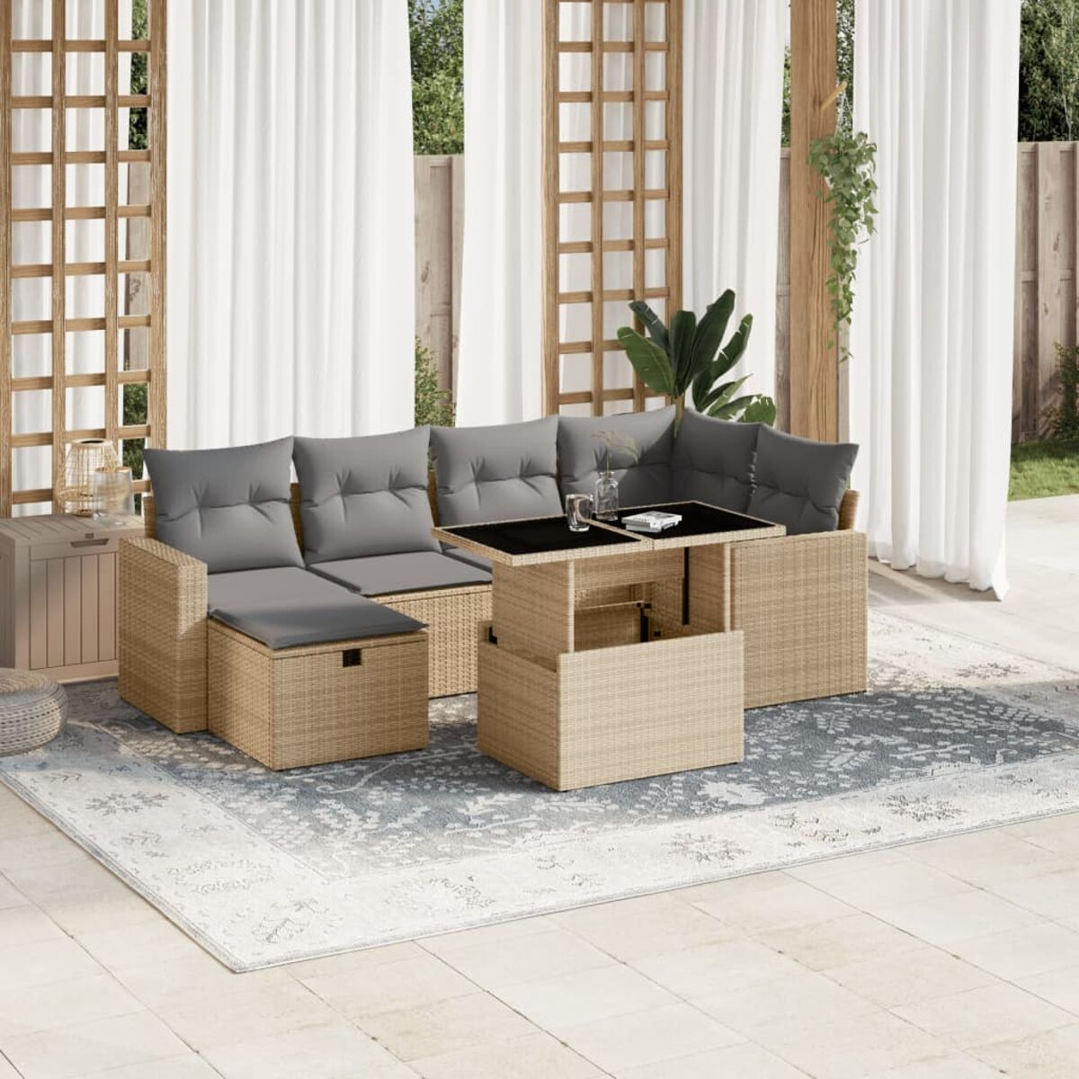 Rattansofa-Set im Freien mit grauen Kissen und einem schwarzen Tisch auf einem gemusterten Teppich.