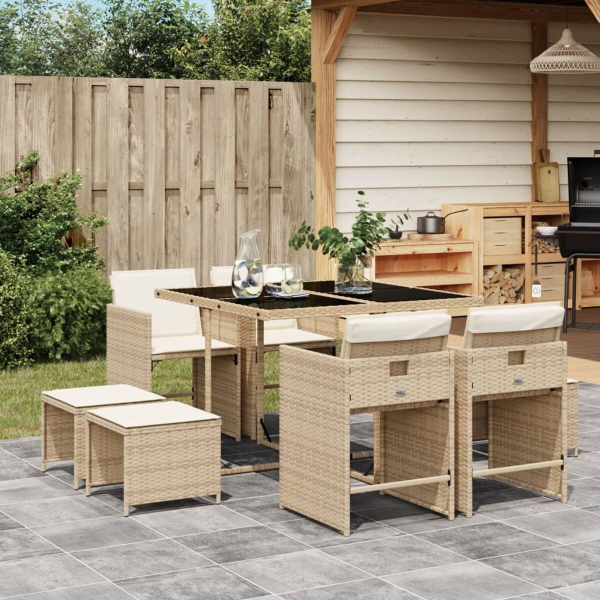 Essgruppe im Freien: Tisch, Stühle und Hocker auf einer Terrasse. Garten mit Unterstand und Grill.