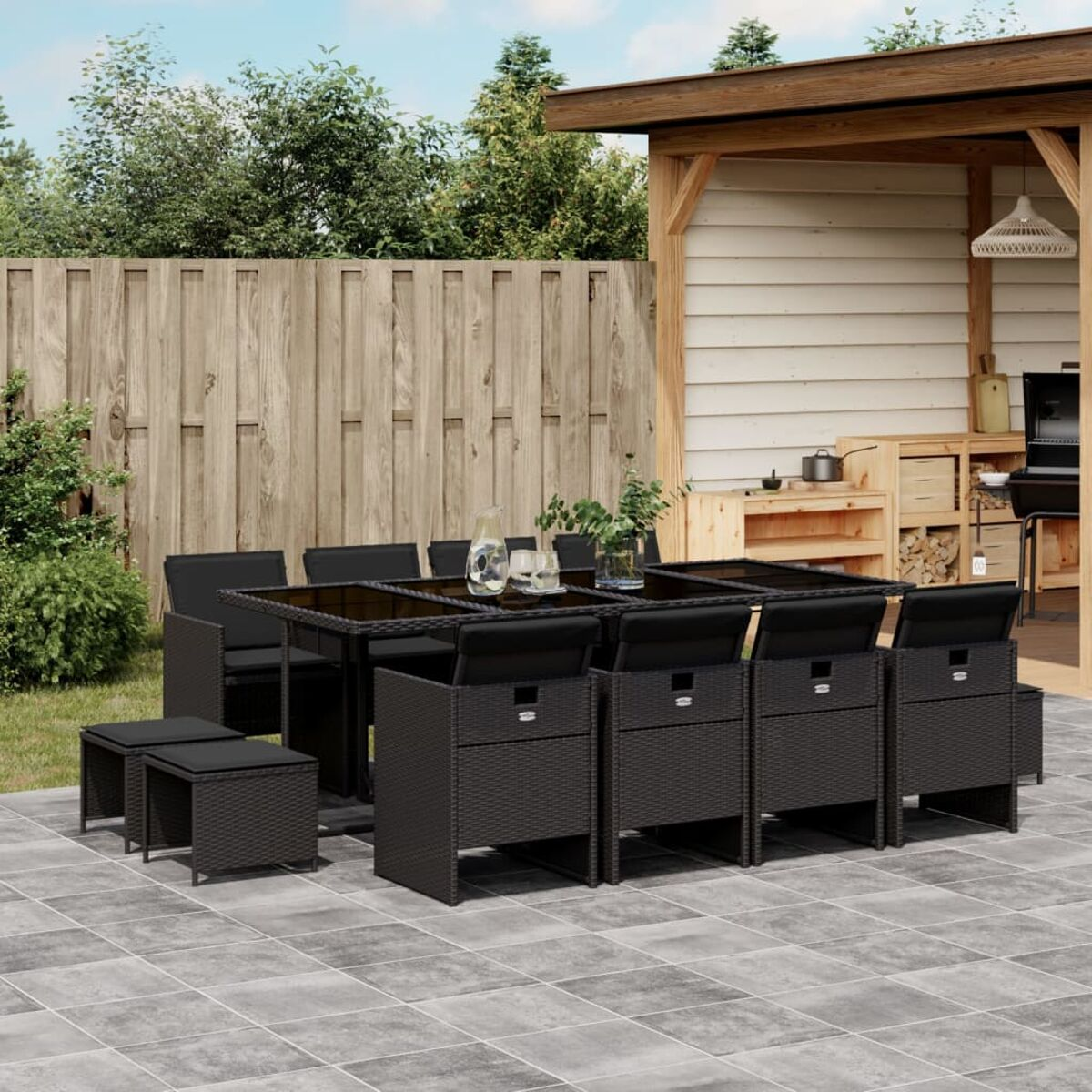 Schwarzes Rattan-Ess-Set für draußen mit Tisch und Stühlen, mit Holzzaun im Hintergrund.