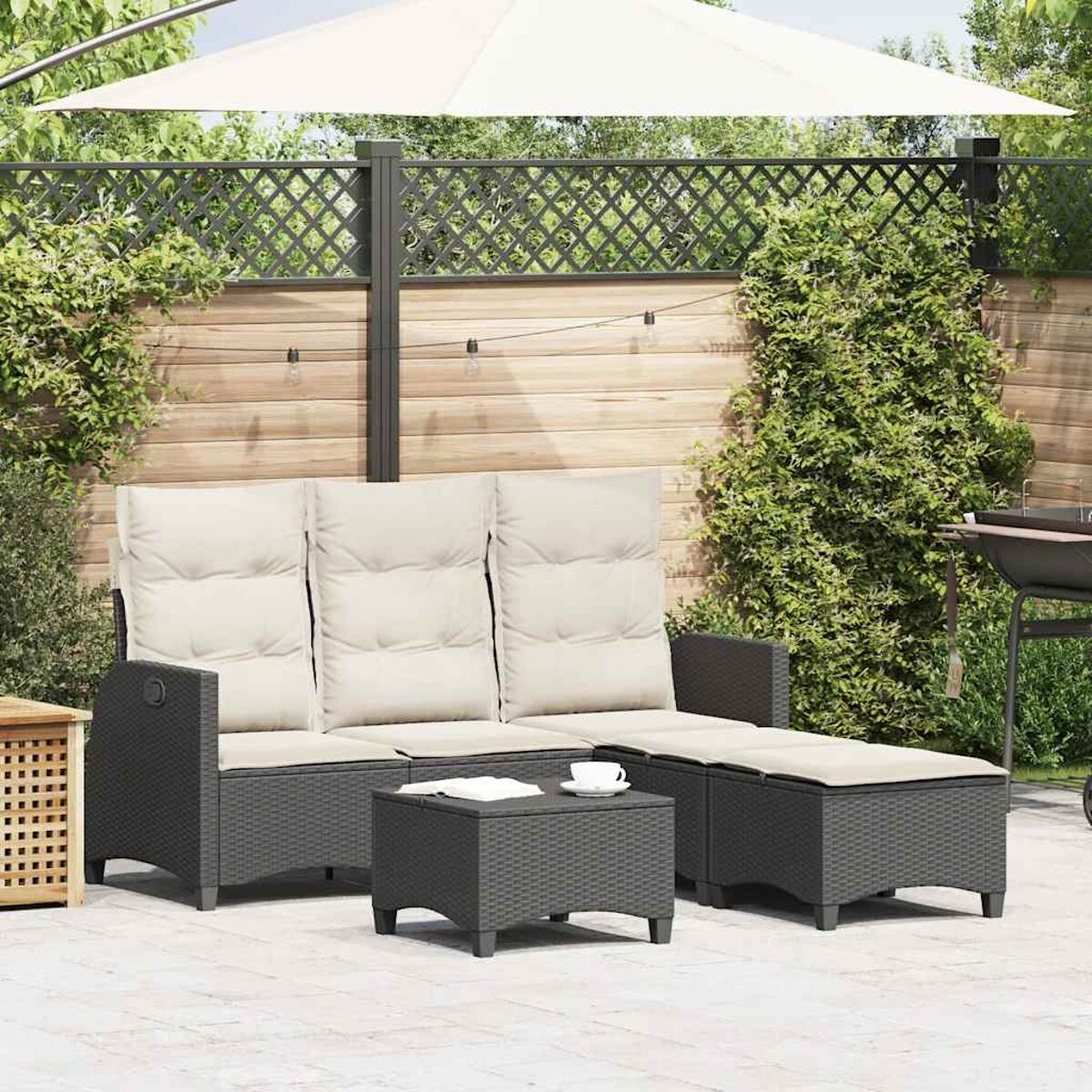 Set living esterno: un divano a tre posti, un tavolino e un pouf. Cuscini beige e un ombrello bianco.