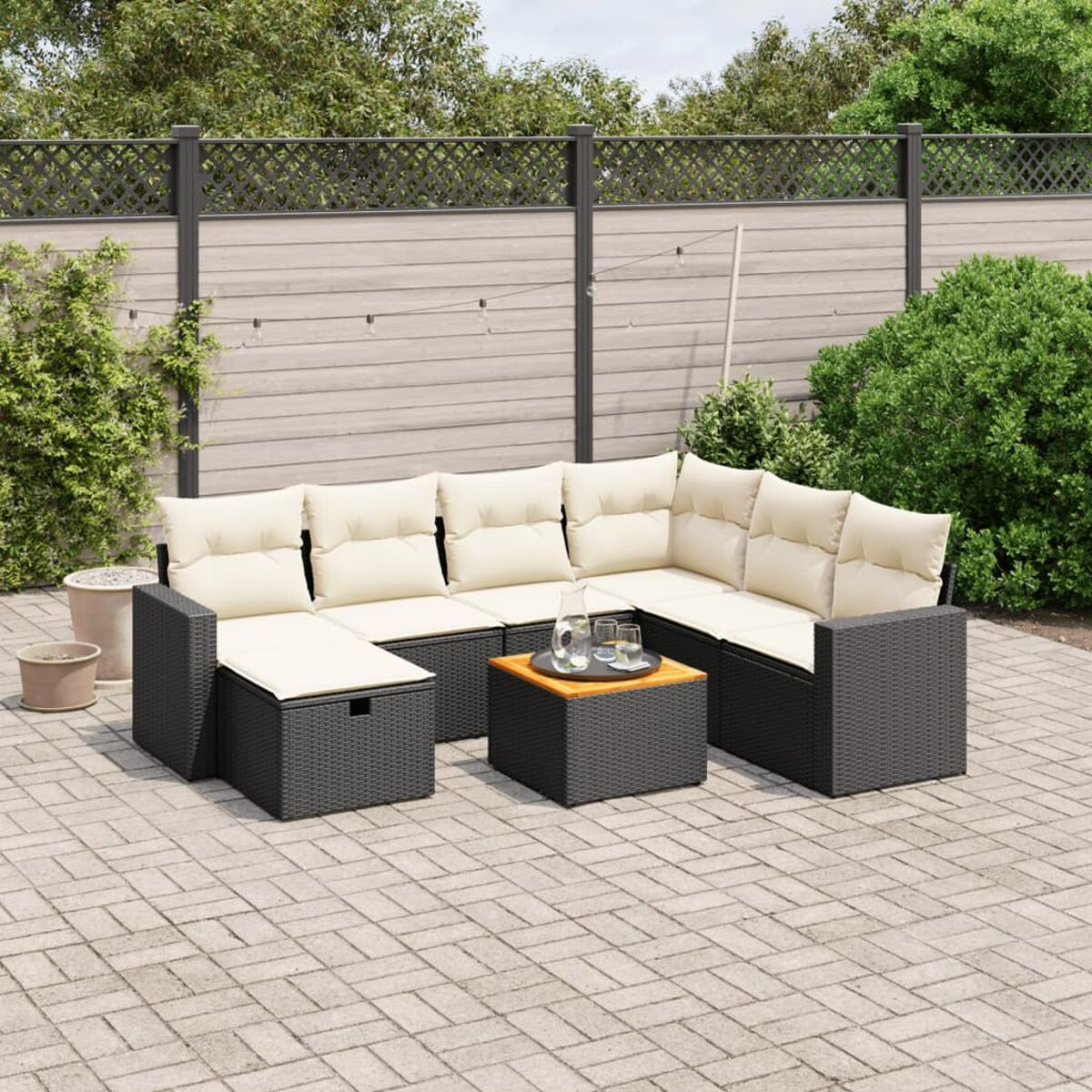 Schwarzes Outdoor-Geflecht-Sofa mit beigen Kissen, Tisch mit Getränken.