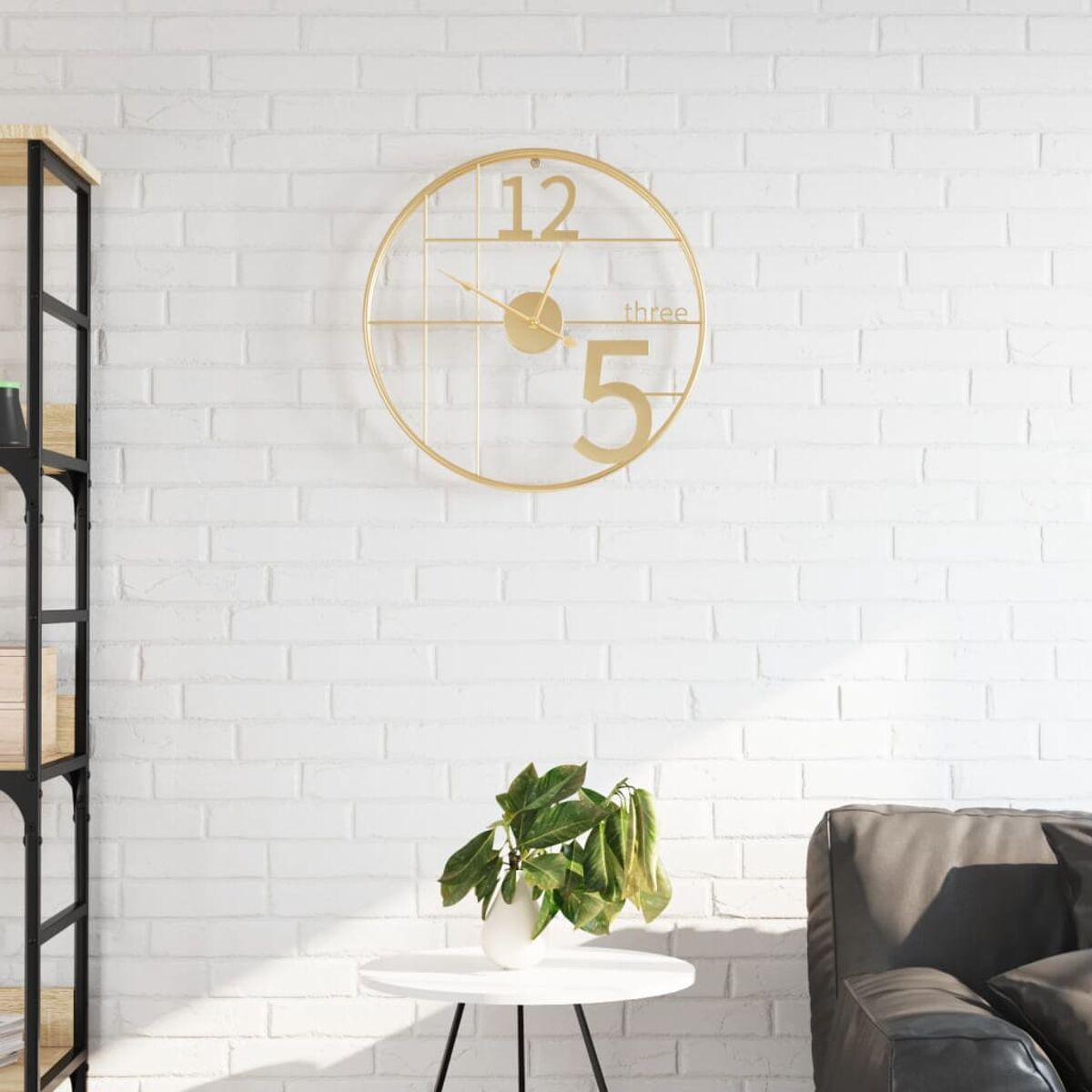Goldene Wanduhr mit großen Zahlen und eine kleine Pflanze auf einem weißen Tisch.