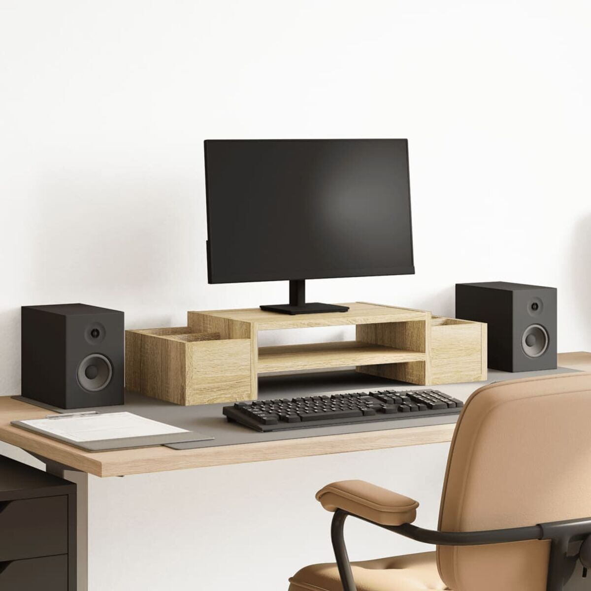 Ein Schreibtisch-Setup mit Monitor, Lautsprechern, Tastatur und Büromaterial.
