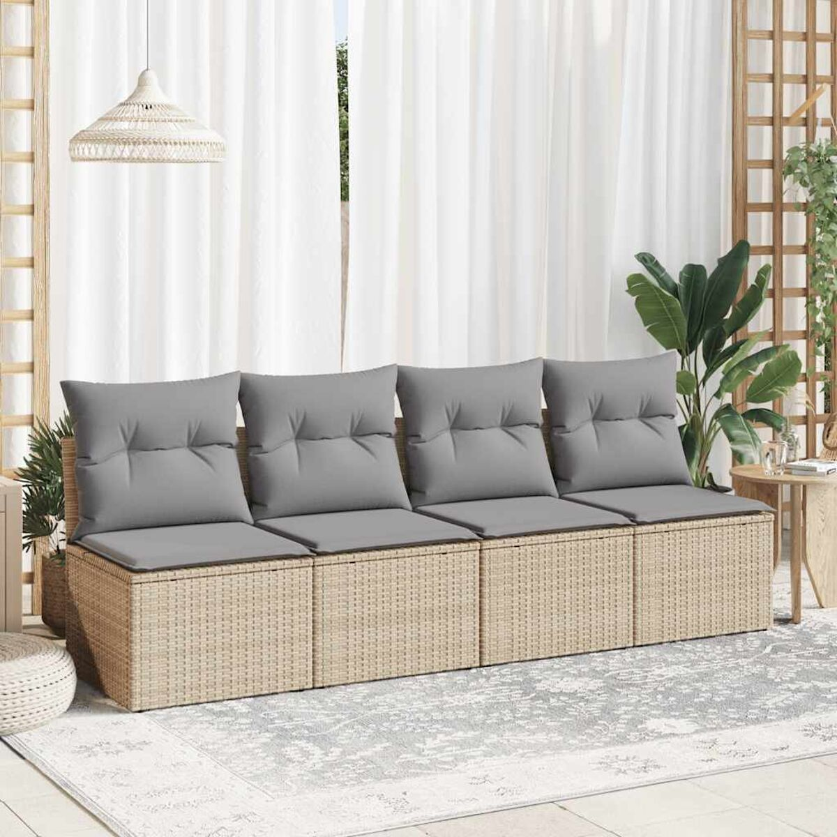 Divano da esterno in vimini beige con quattro cuscini grigi, su un tappeto grigio.