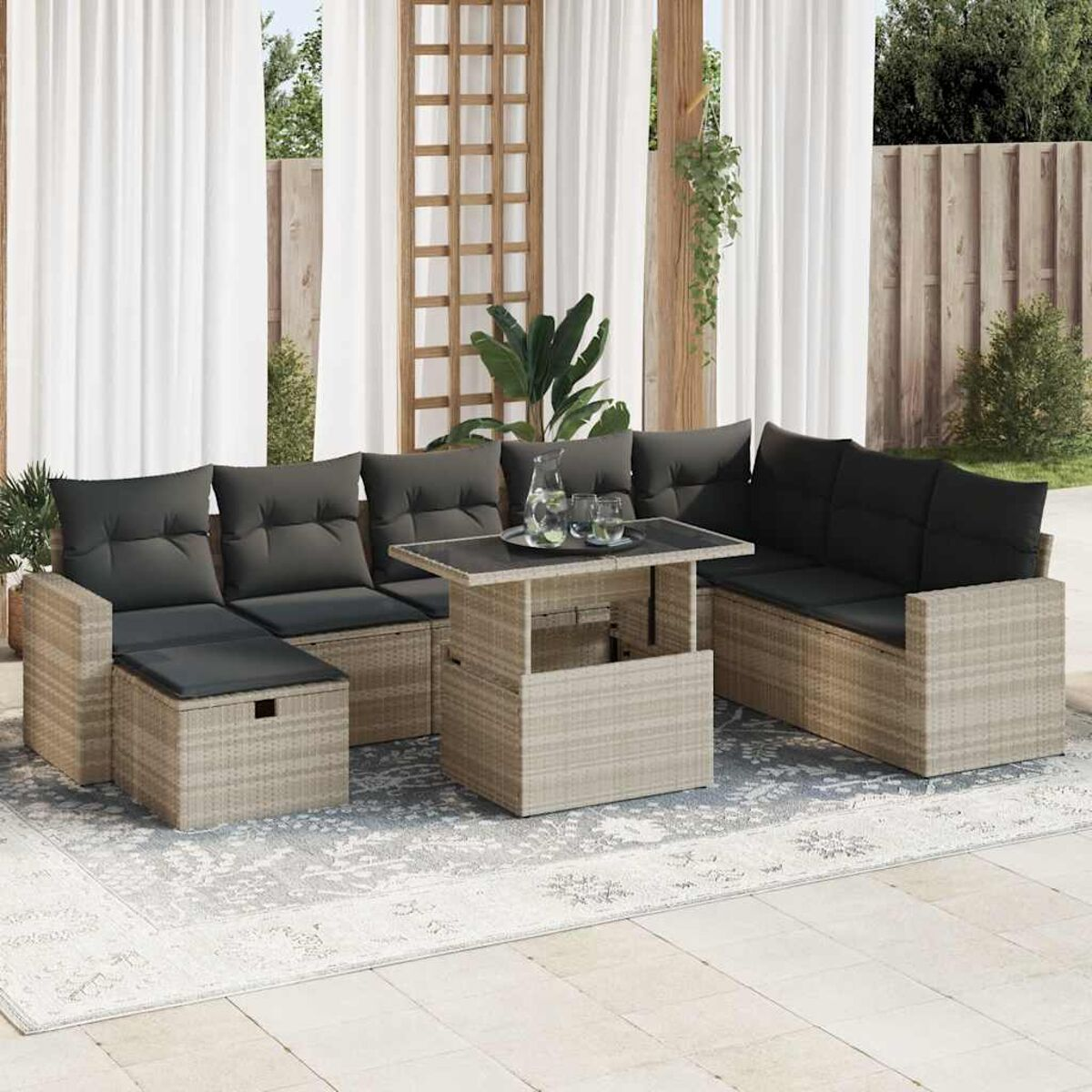 Outdoor-Korbmöbel-Set mit grauen Kissen und einem Tisch. Auf einem gemusterten Teppich. Draufsicht.