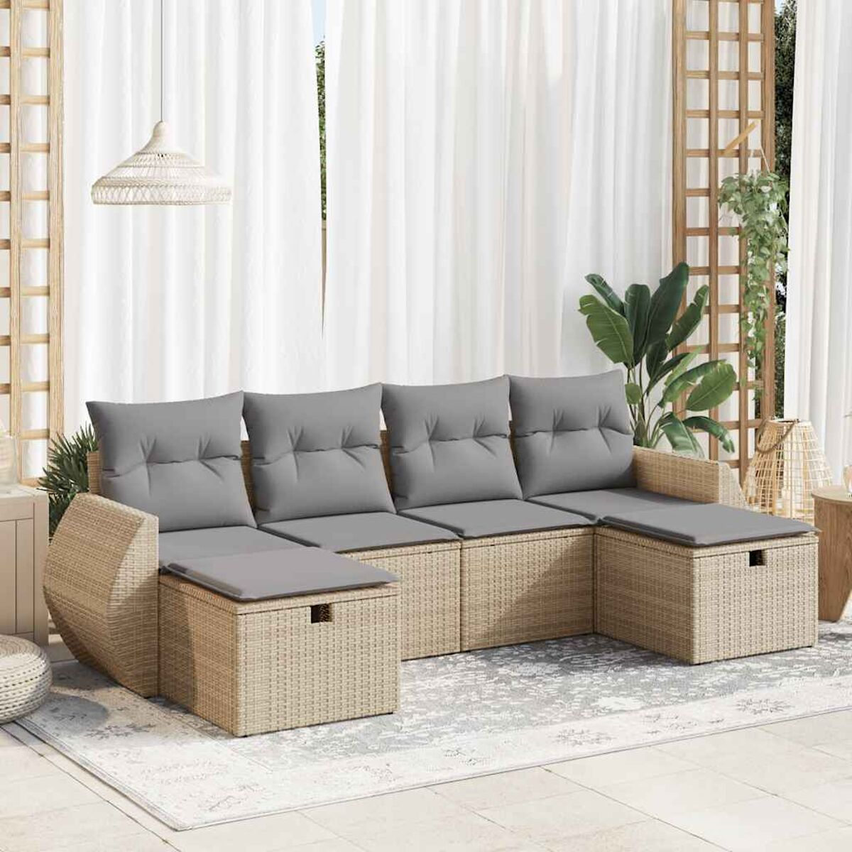 Geflochtenes Ecksofa mit grauen Kissen auf einer Terrasse. Inklusive Teppich und weißem Vorhang.