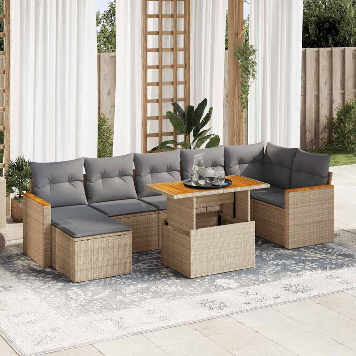 Set divano componibile in rattan con tavolino sollevabile e cuscini grigi. Ambiente esterno sul patio.