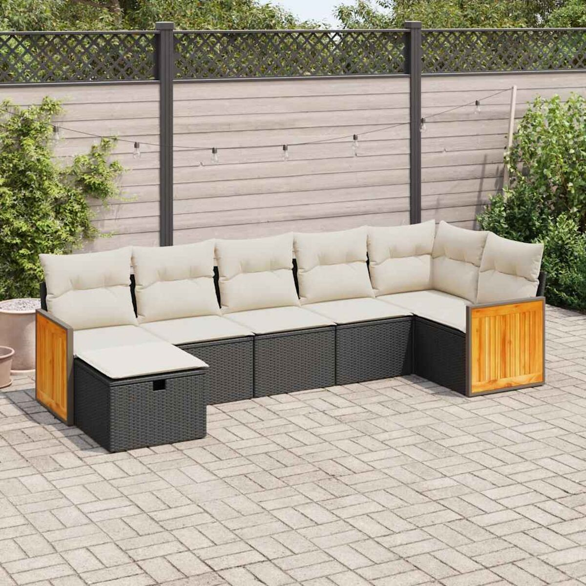 Schwarzes und graues Outdoor-Sofaset mit beigen Kissen, angeordnet auf einer Ziegelterrasse.