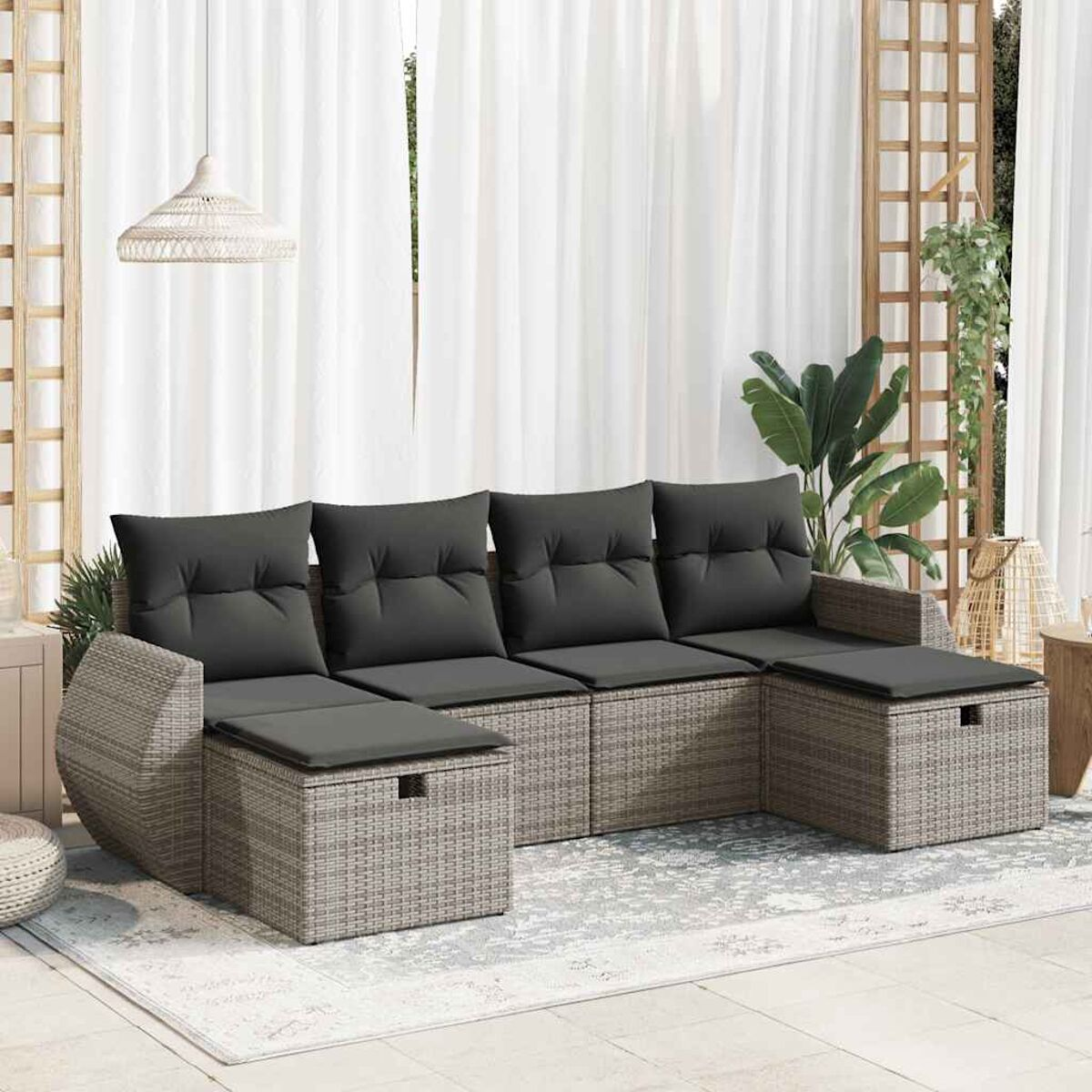 Outdoor-Sofaset im Rattanstil mit grauen Kissen und einem Couchtisch. Mit einem Teppich.