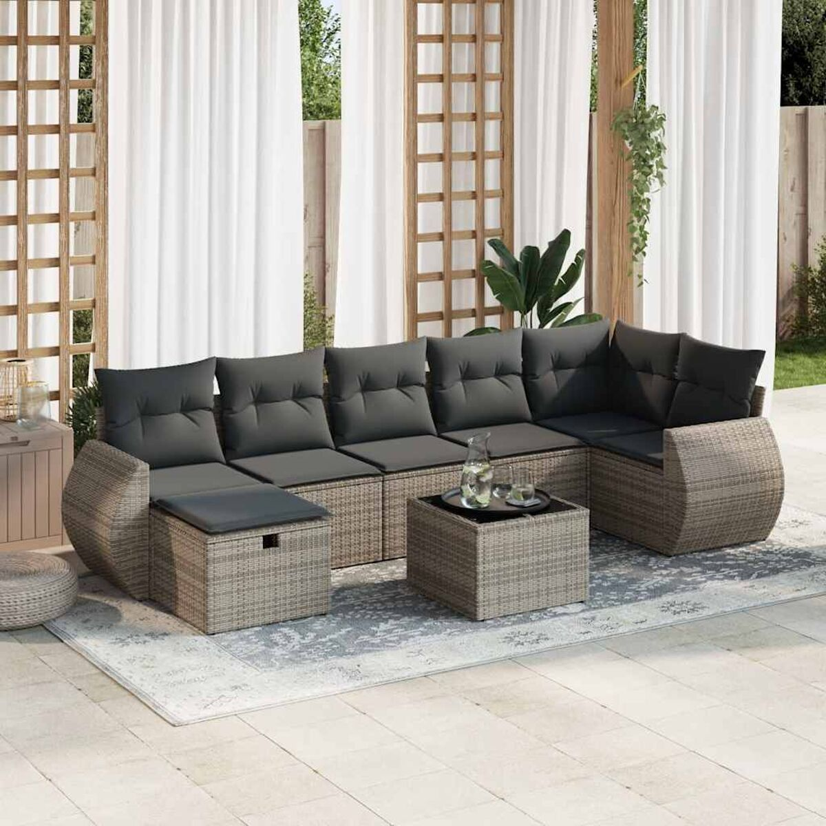 Ein Ecksofa aus Korbgeflecht mit dunkelgrauen Kissen und einem quadratischen Couchtisch.