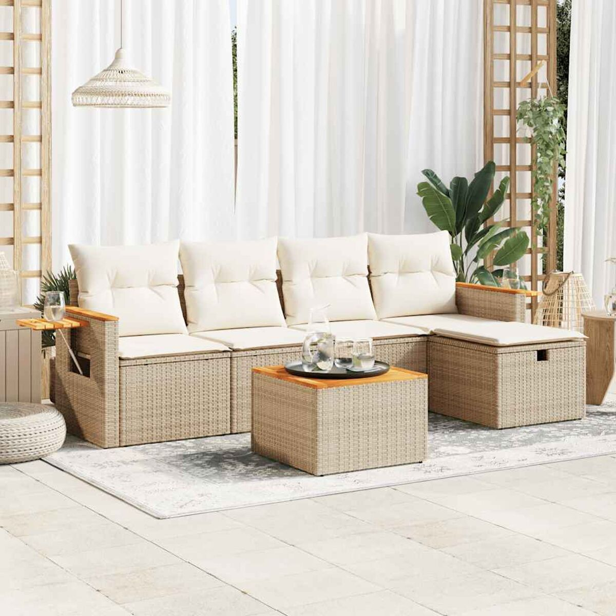Geflochtenes Outdoor-Sofaset mit Tisch und Teppich. Weiße Vorhänge und Terrasse. Ein Glas Wasser auf dem Tisch.
