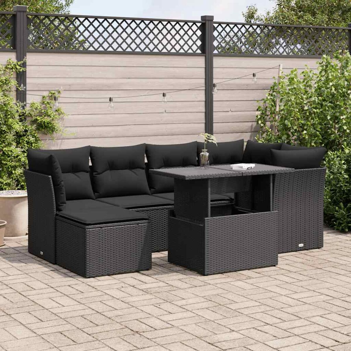 Un set da esterno in vimini nero con un tavolo elevabile e un divano. Il set è su un'area pavimentata.