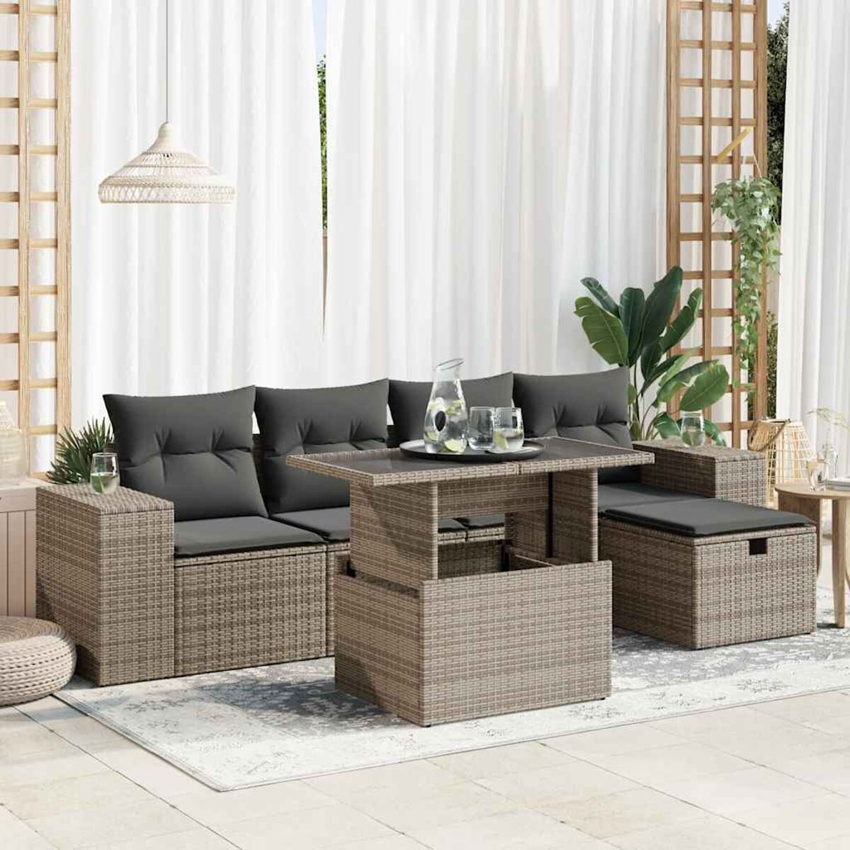 Gartenmöbel-Set mit grauen Kissen und einem Tisch. Auf dem Boden liegt ein Teppich.