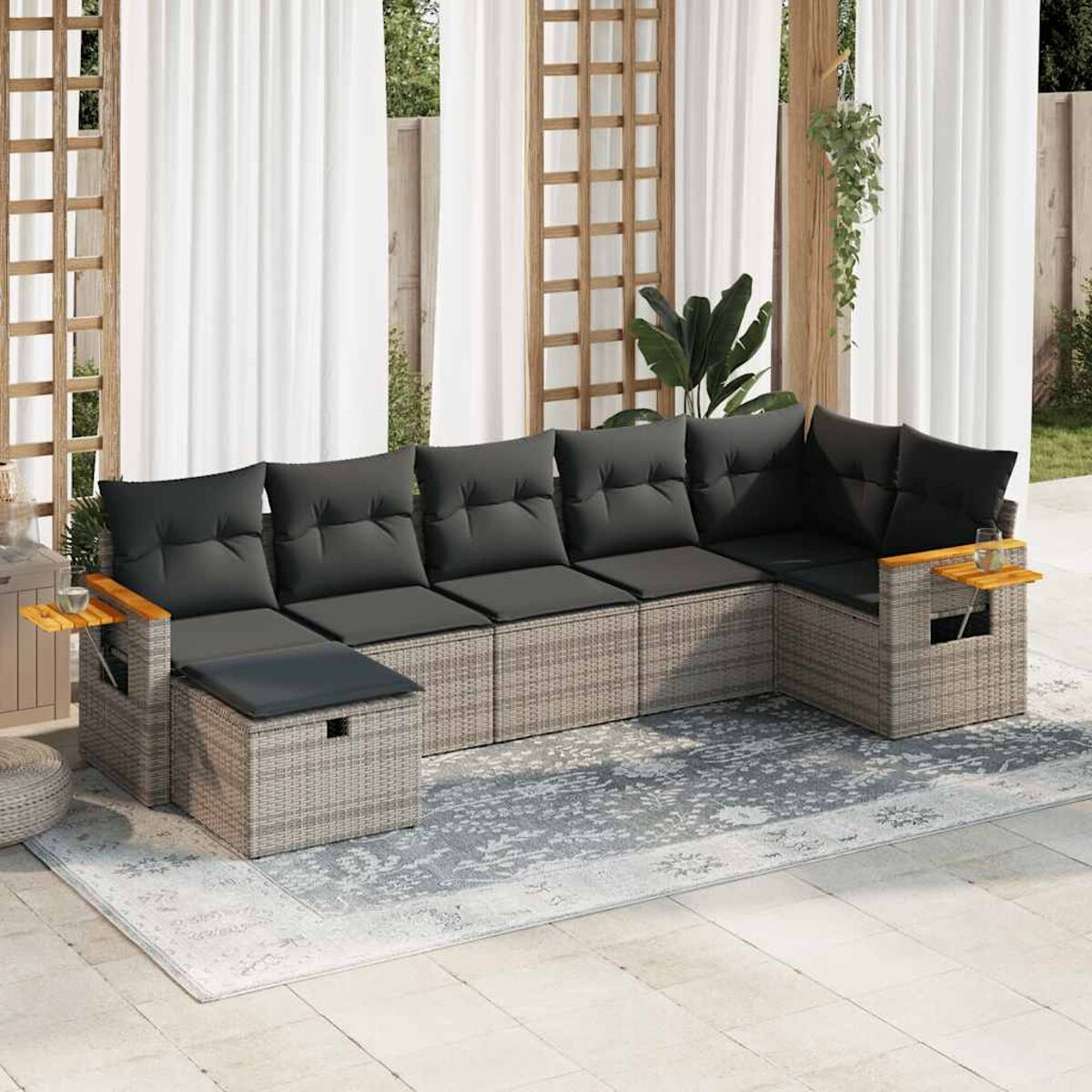 Graues Korbmöbel-Ecksofa mit dunkelgrauen Kissen und Beistelltischen auf Terrasse.