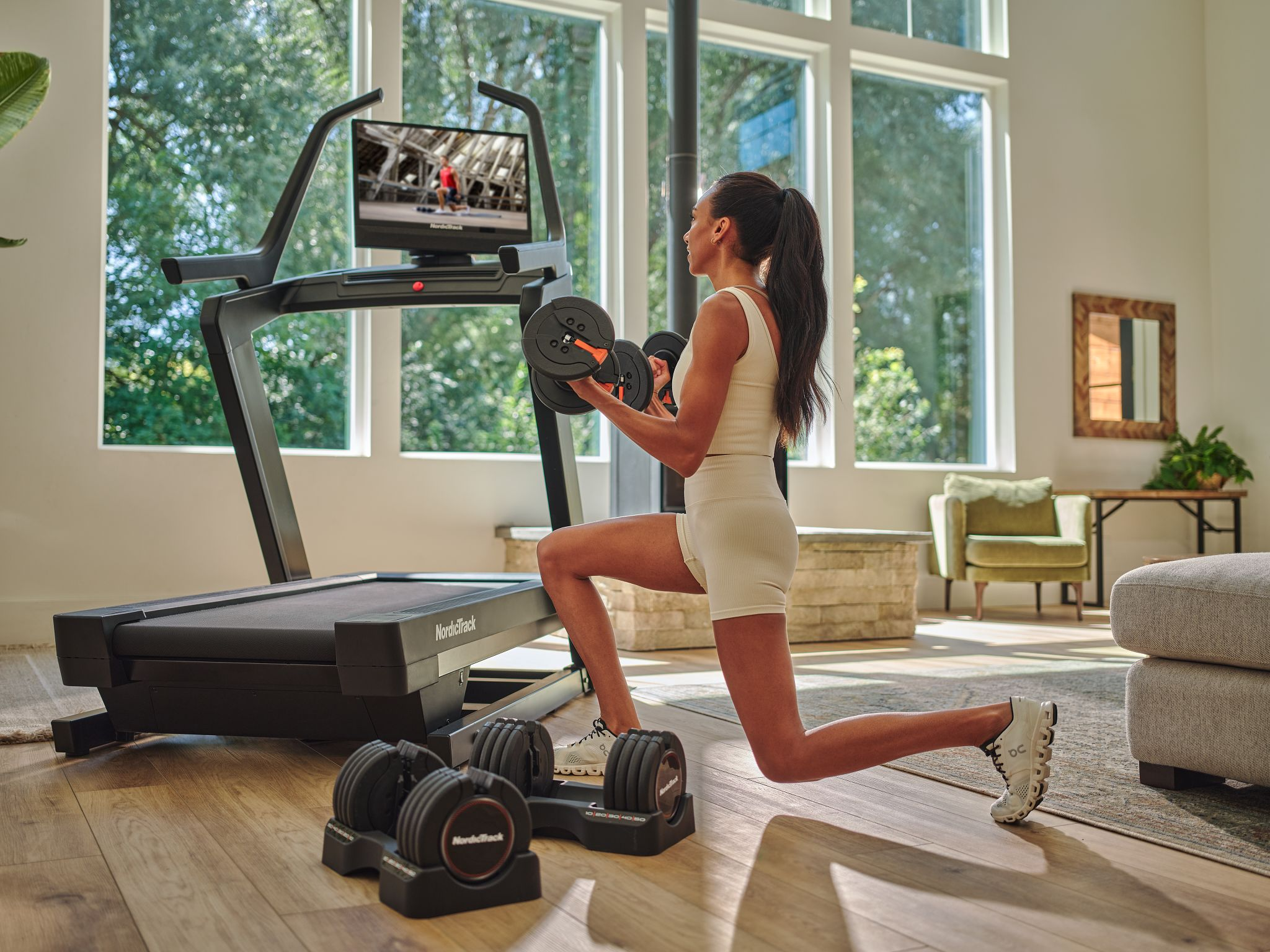 Eine Frau trainiert mit Gewichten auf einem Laufband. Eine Heimtrainingseinrichtung.