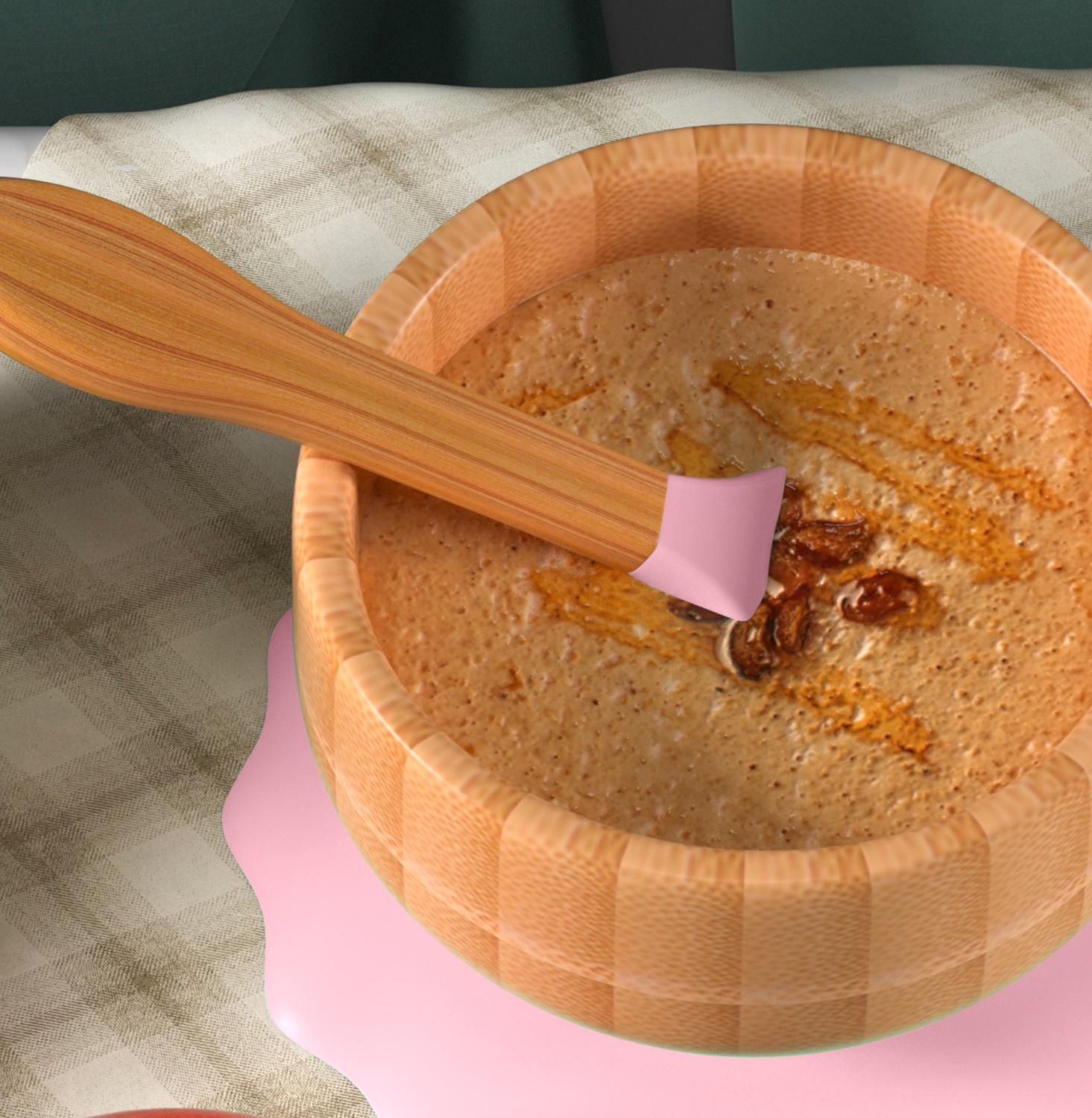 Eine Holzschüssel mit Essen und ein Holzlöffel mit rosa Silikonspitze.