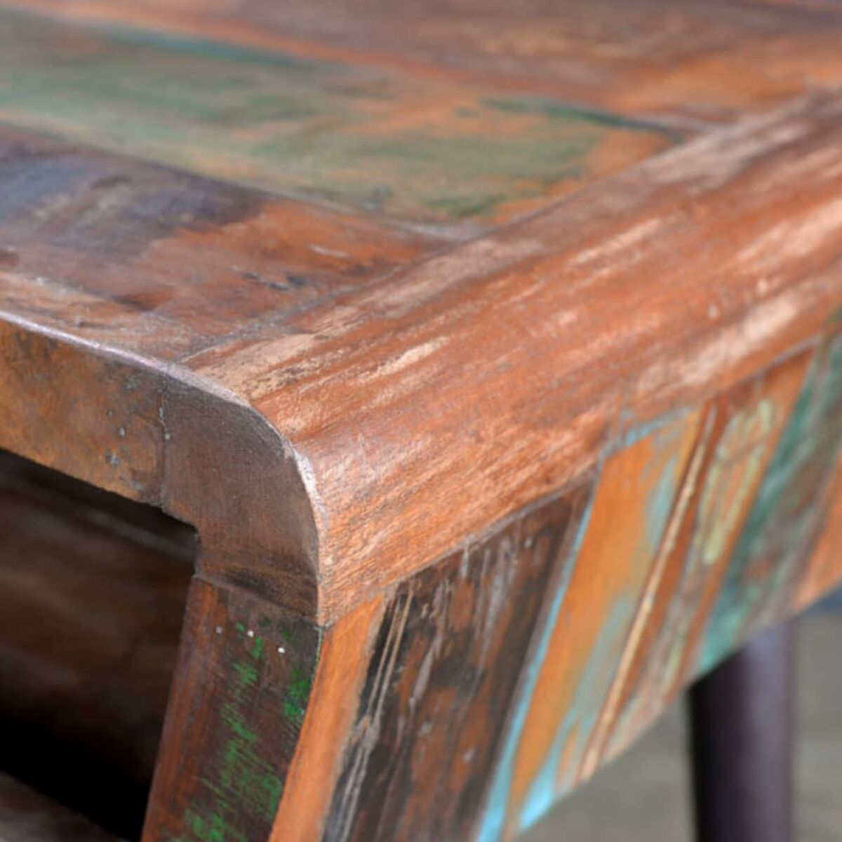 Nahaufnahme einer Tischoberfläche mit abgenutztem, mehrfarbigem Holzfinish.