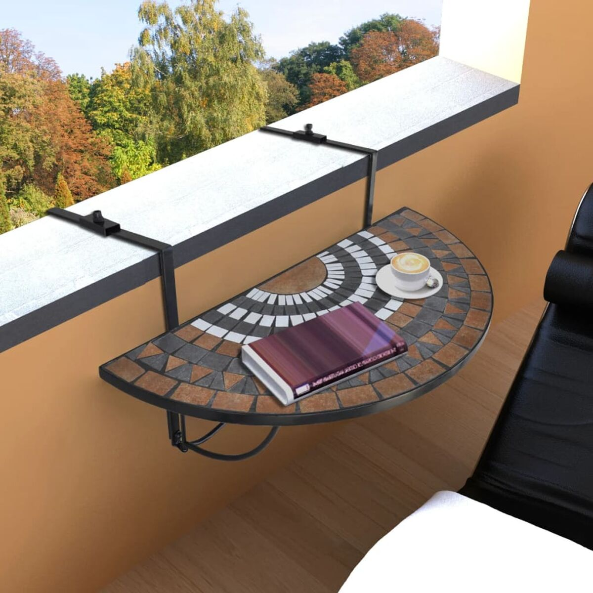 Halbkreisförmiger Balkontisch mit Mosaikplatte. Buch und Tasse darauf. Braune, weiße und schwarze Fliesen. Schwarzes Geländer.