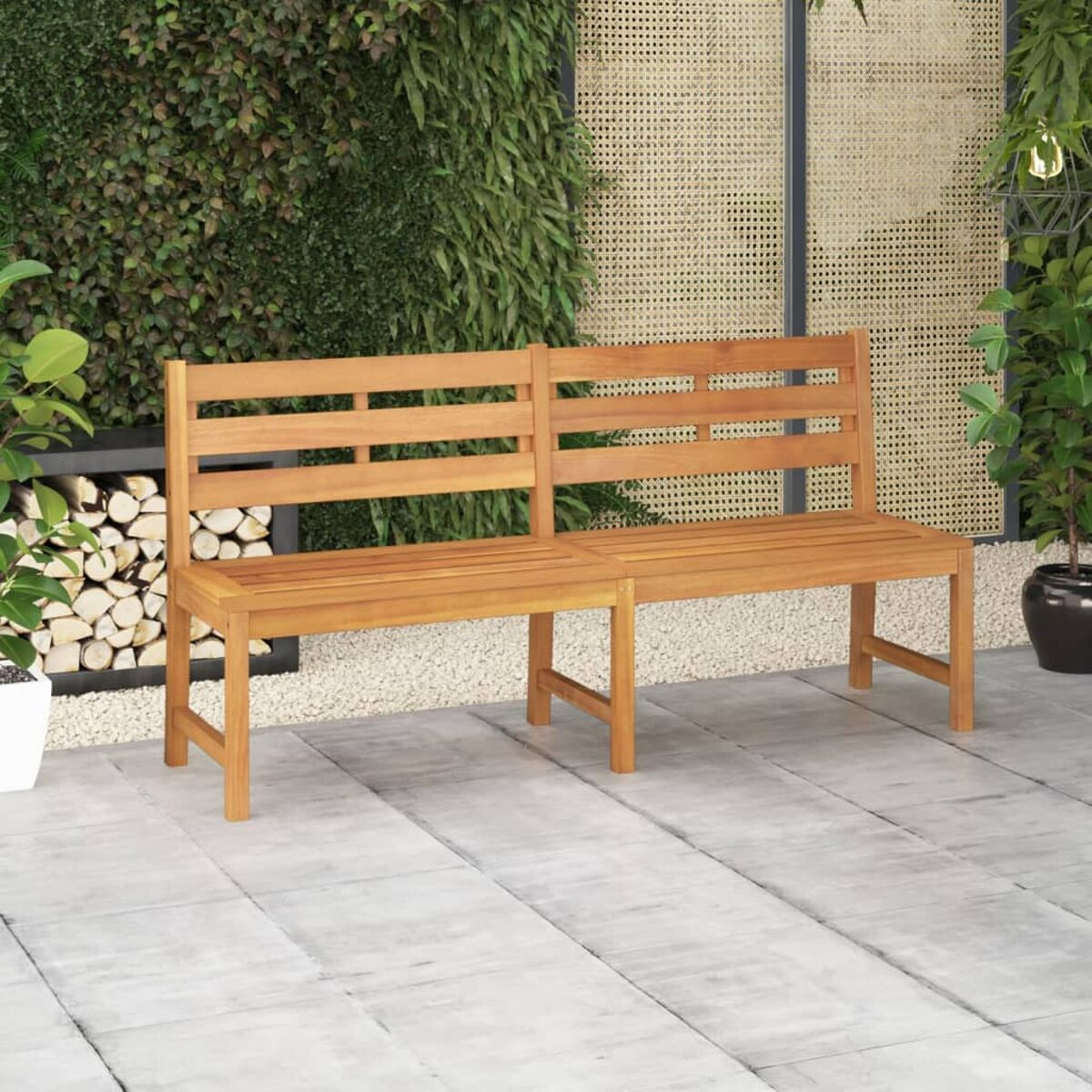 Eine Holzbank mit zwei Sitzteilen. Sie steht auf einer Terrasse mit Pflanzen im Hintergrund.