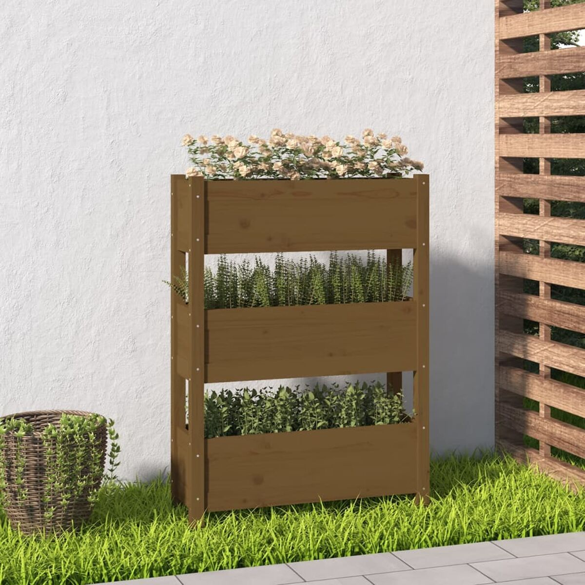 Brauner Pflanzkasten aus Holz mit Blumen und Pflanzen. Der Hintergrund ist eine weiße Wand und Rasen.
