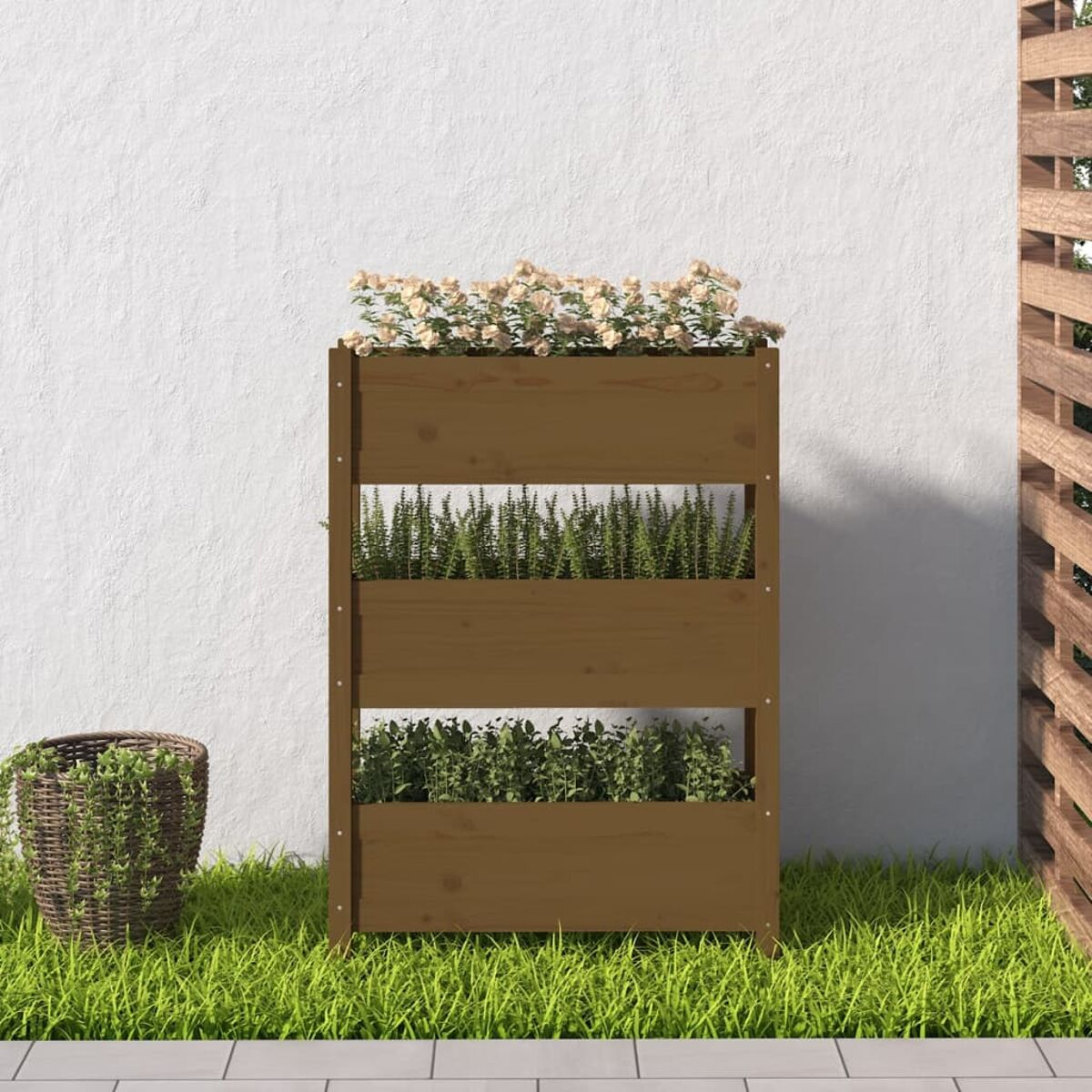 Vertikaler Holzpflanzer mit drei Pflanzenebenen. Weißer Wandhintergrund und Gras.