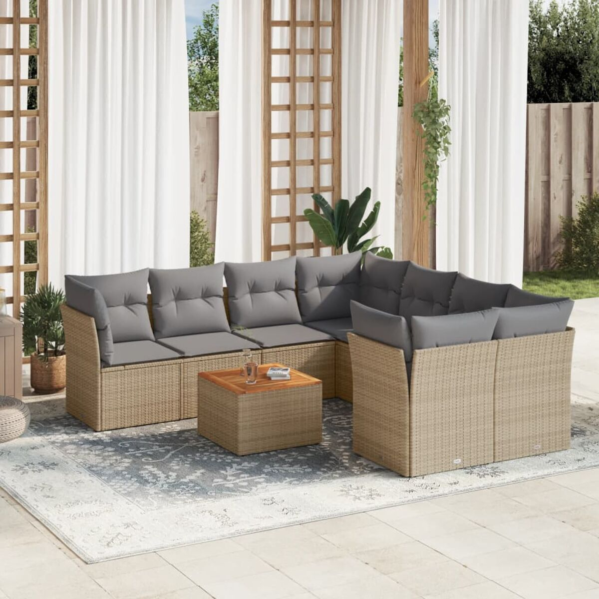 Ein Outdoor-Korbmöbelset mit grauen Kissen und einem Holztisch. Weiße Vorhänge im Hintergrund.