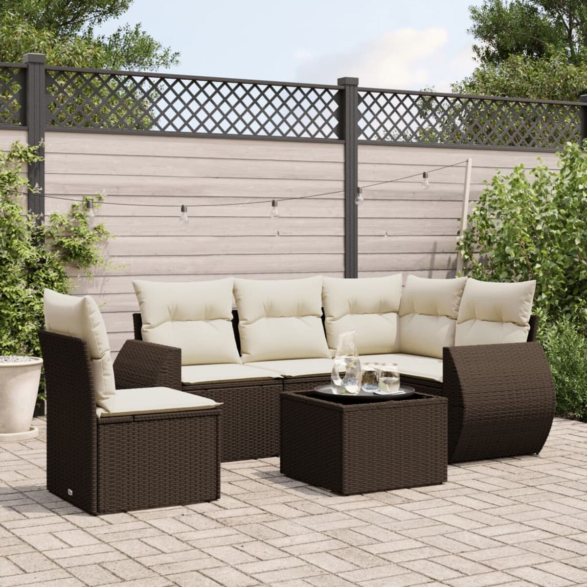 Set patio esterno, vimini marrone. Include divano, sedia e tavolino quadrato. Cuscini bianchi, patio in mattoni.