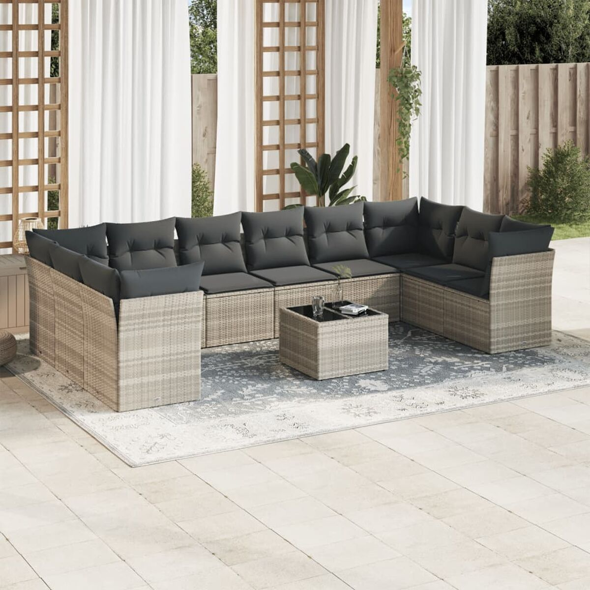 Set da patio esterno con cuscini grigi, un tavolo e un tappeto. Mobili in vimini beige.