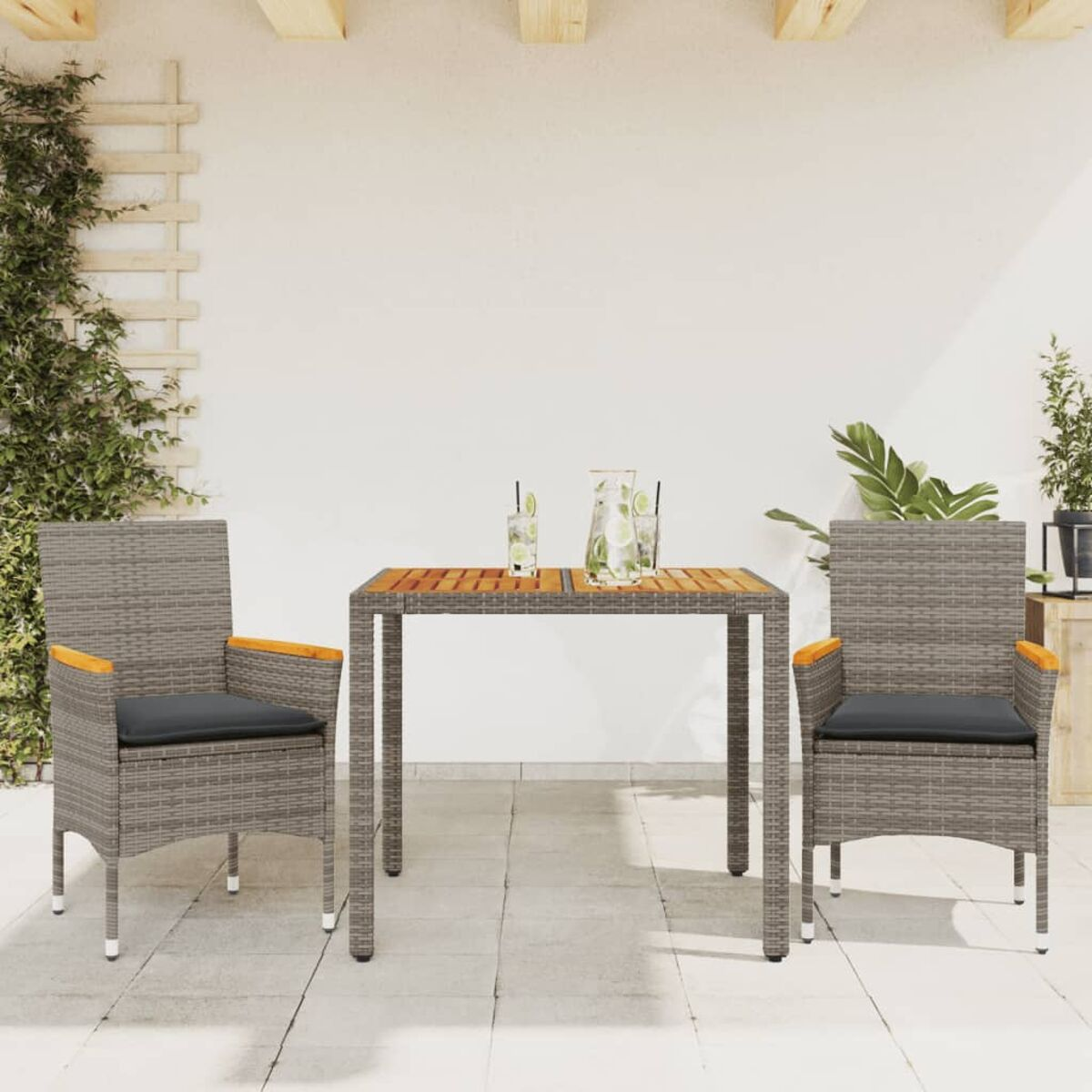 Ein Terrassenset mit Tisch und zwei Stühlen. Die Stühle haben Kissen. Die Umgebung ist sonnig.