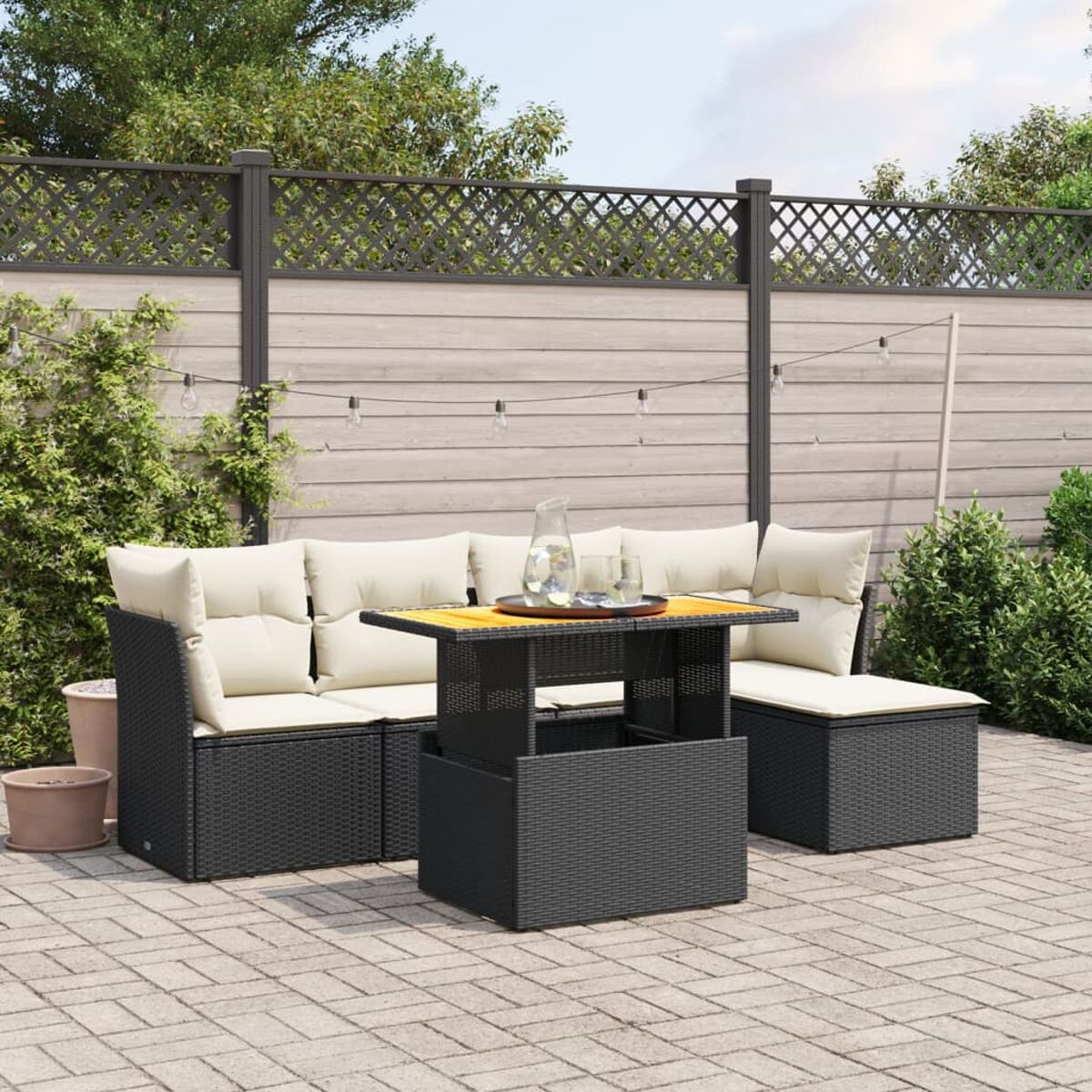 Schwarzes Outdoor-Wicker-Sofaset mit Tisch. Garteneinstellung mit Zaun.