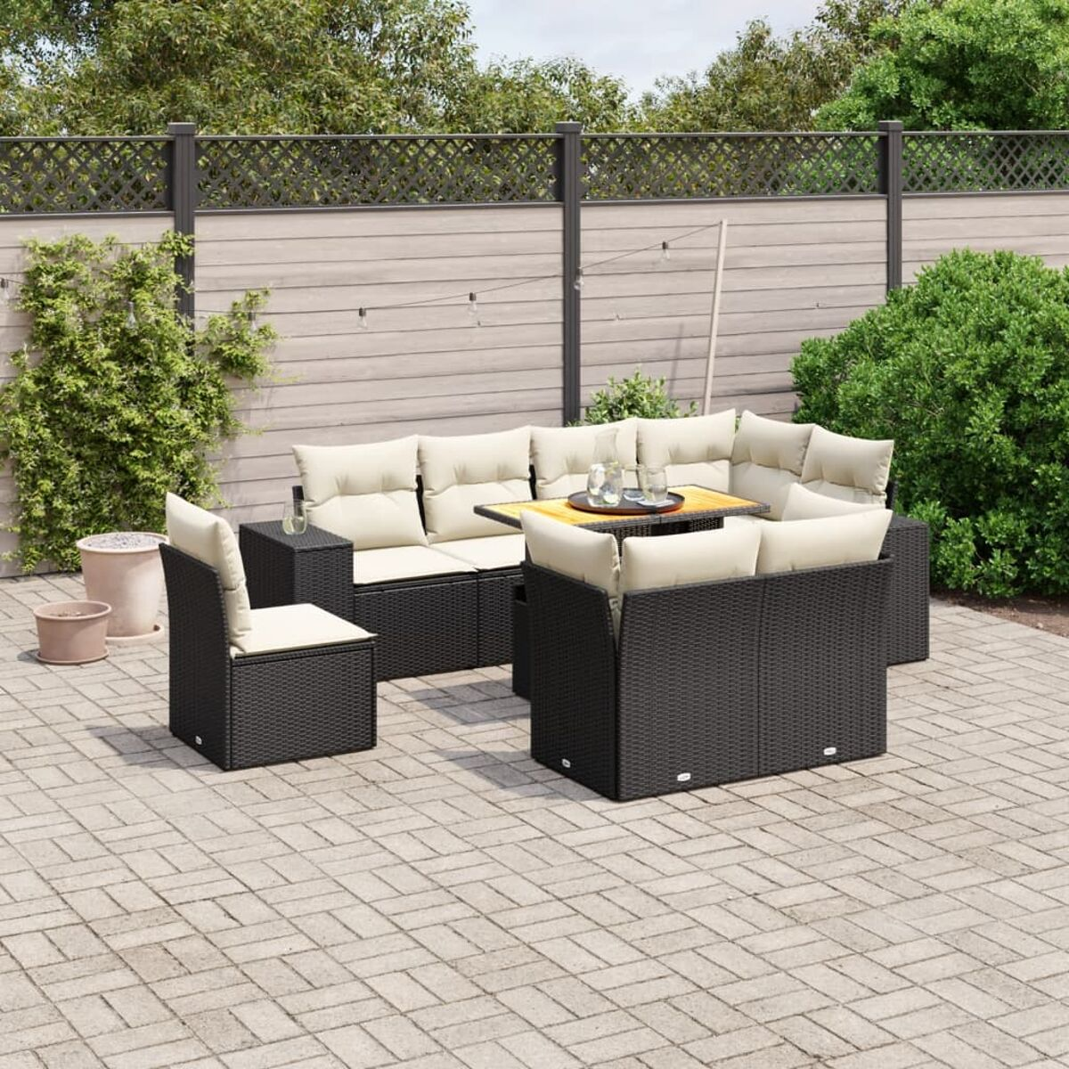 Schwarzes Gartenmöbel-Set mit Tisch und cremefarbenen Kissen, auf einer Terrasse.