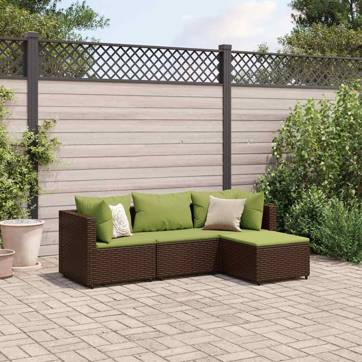 Divano componibile in vimini marrone con cuscini verdi. Cuscini beige, patio in mattoni.