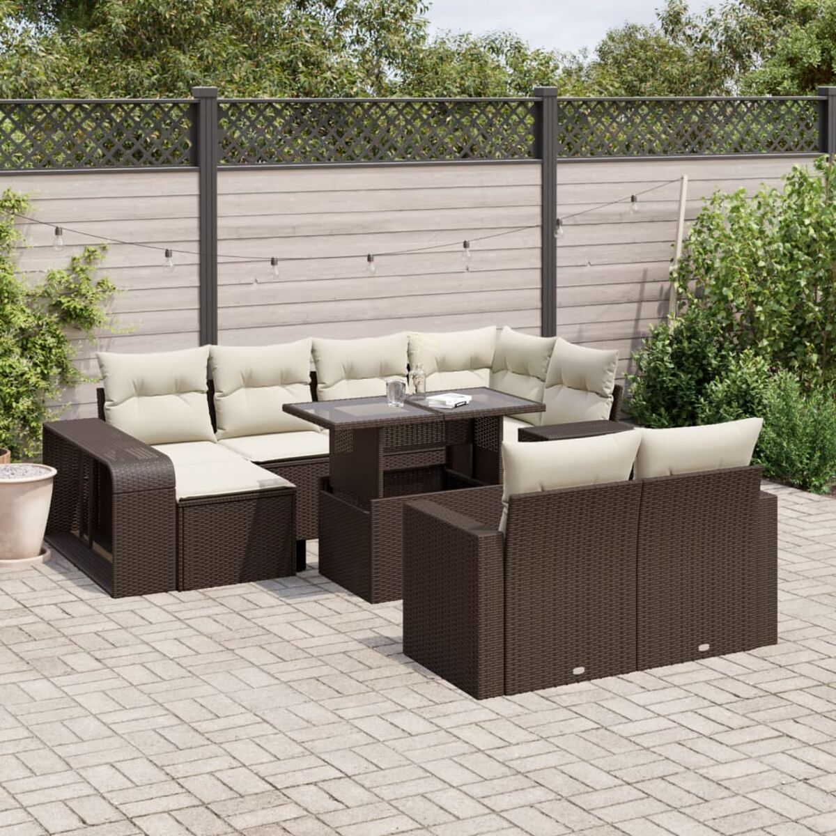 Braunes Outdoor-Sofaset aus Korbgeflecht mit beigen Kissen und Tisch auf gepflasterter Terrasse.