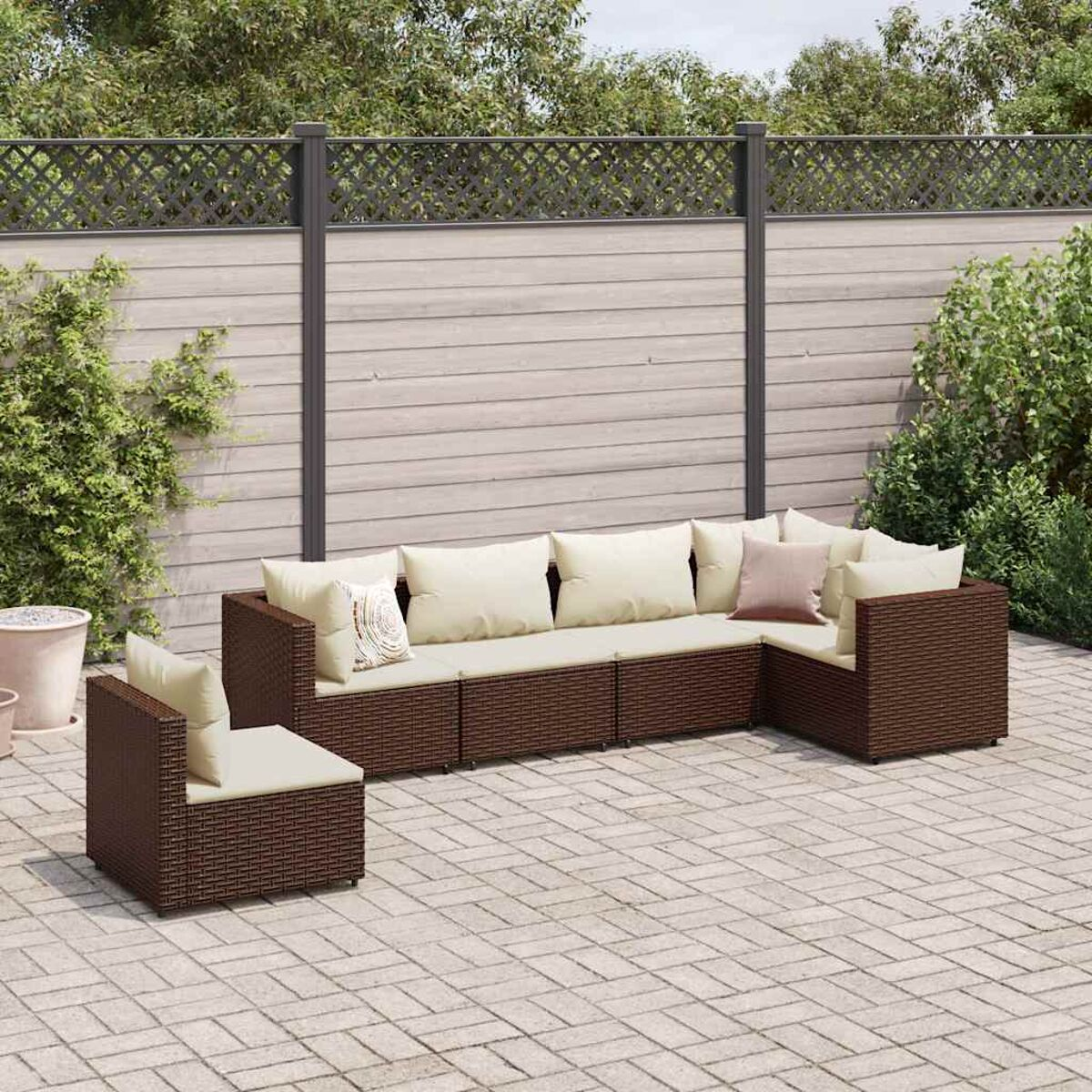 Sofá seccional para exteriores con cojines beige. Marco de mimbre marrón. Patio de ladrillo.