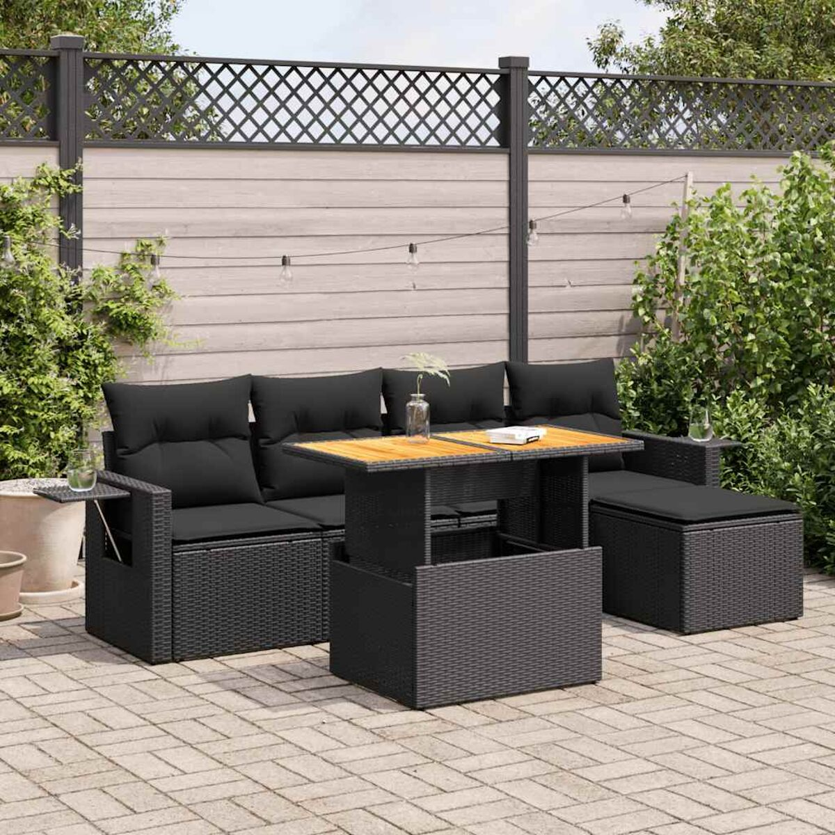 Schwarze Outdoor-Sofagarnitur aus Rattan mit einem Couchtisch. Das Set hat schwarze Kissen.