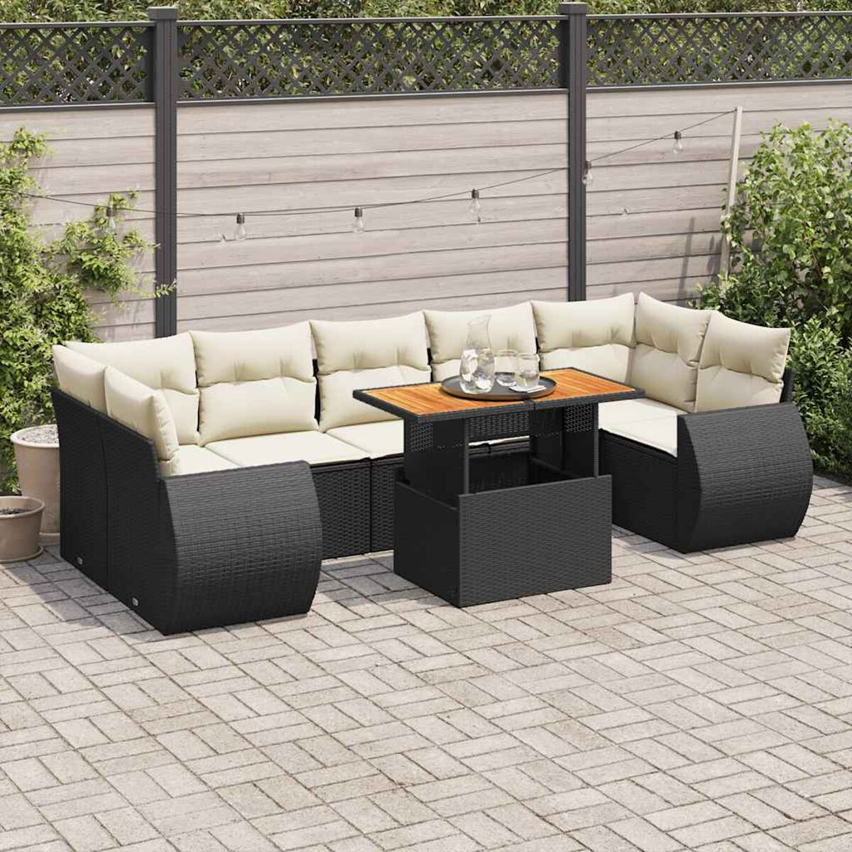 Divano componibile da esterno in vimini nero con cuscini beige e tavolo in legno.
