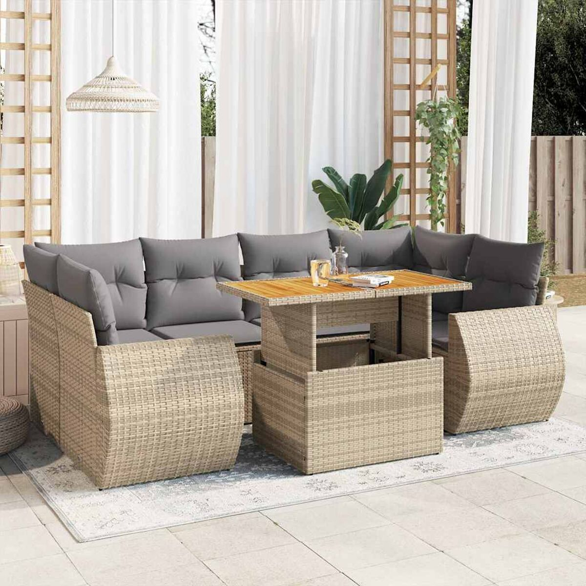 Terrassenset mit hellen Korbmöbeln, grauen Kissen und einem Holztisch. Weiße Vorhänge im Hintergrund.