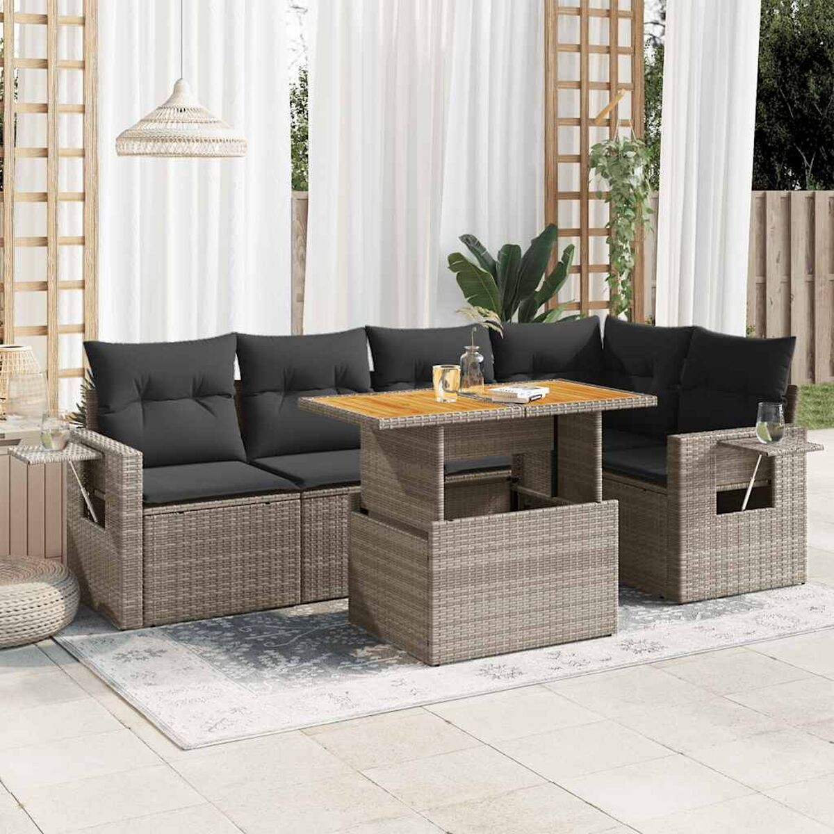 Set di divani in vimini da esterno con tavolo, cuscini ed elementi decorativi.