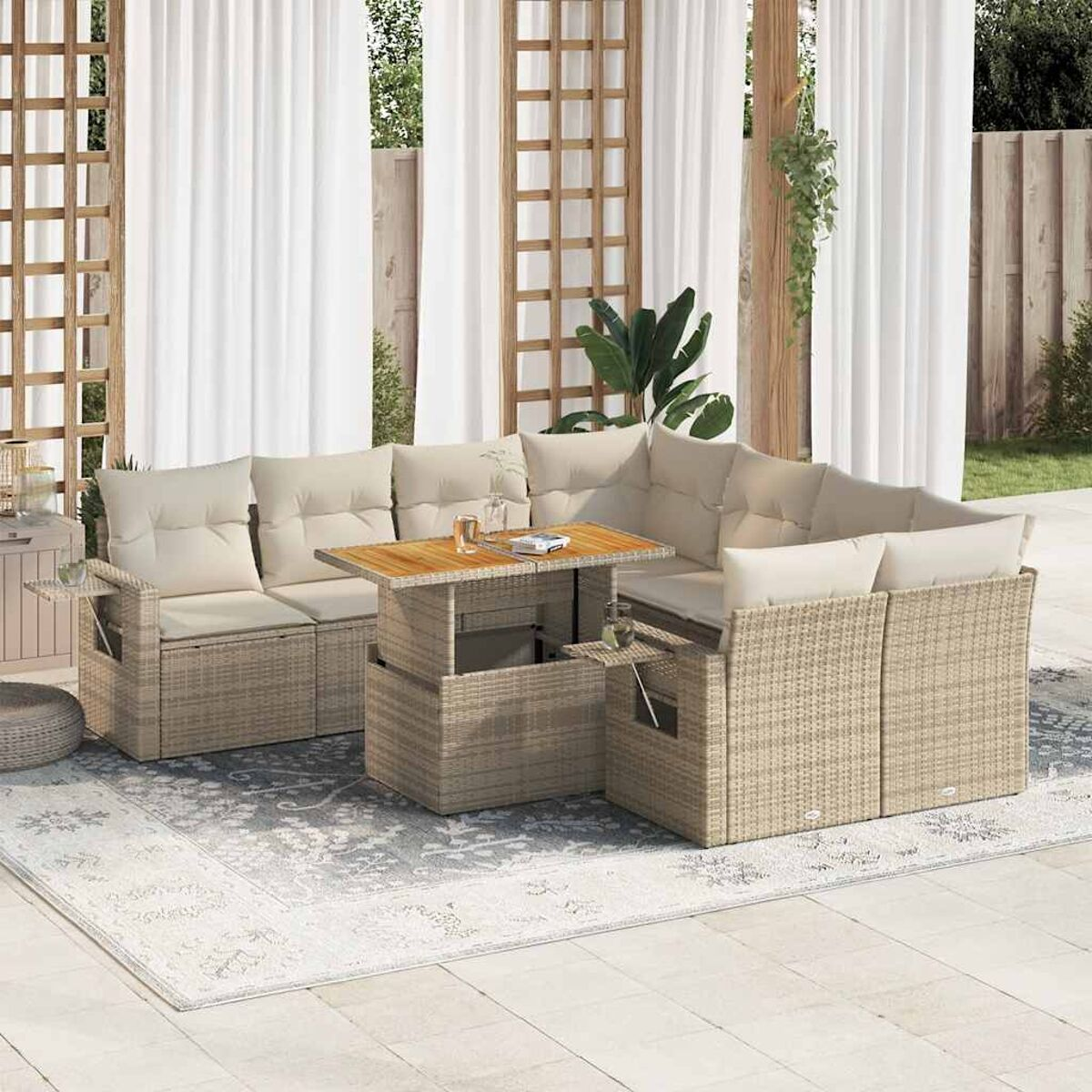 Divano componibile da esterno in rattan beige con cuscini e un tavolo in legno. Un tappeto bianco sotto.