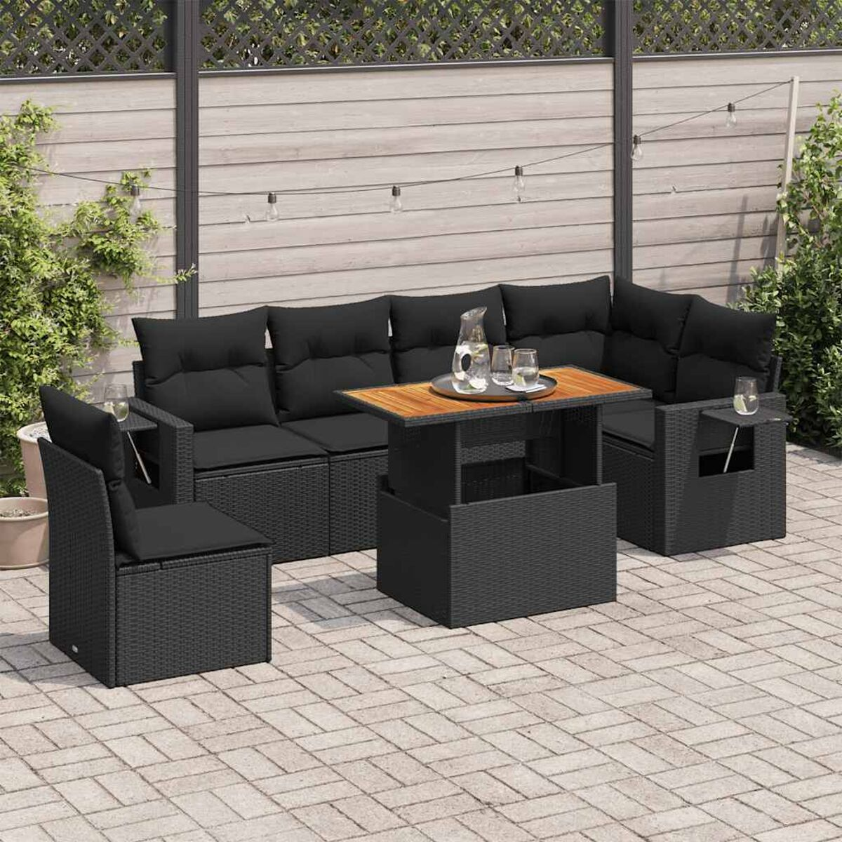 Set divano da esterno in rattan nero con tavolino. Il set ha cuscini neri.