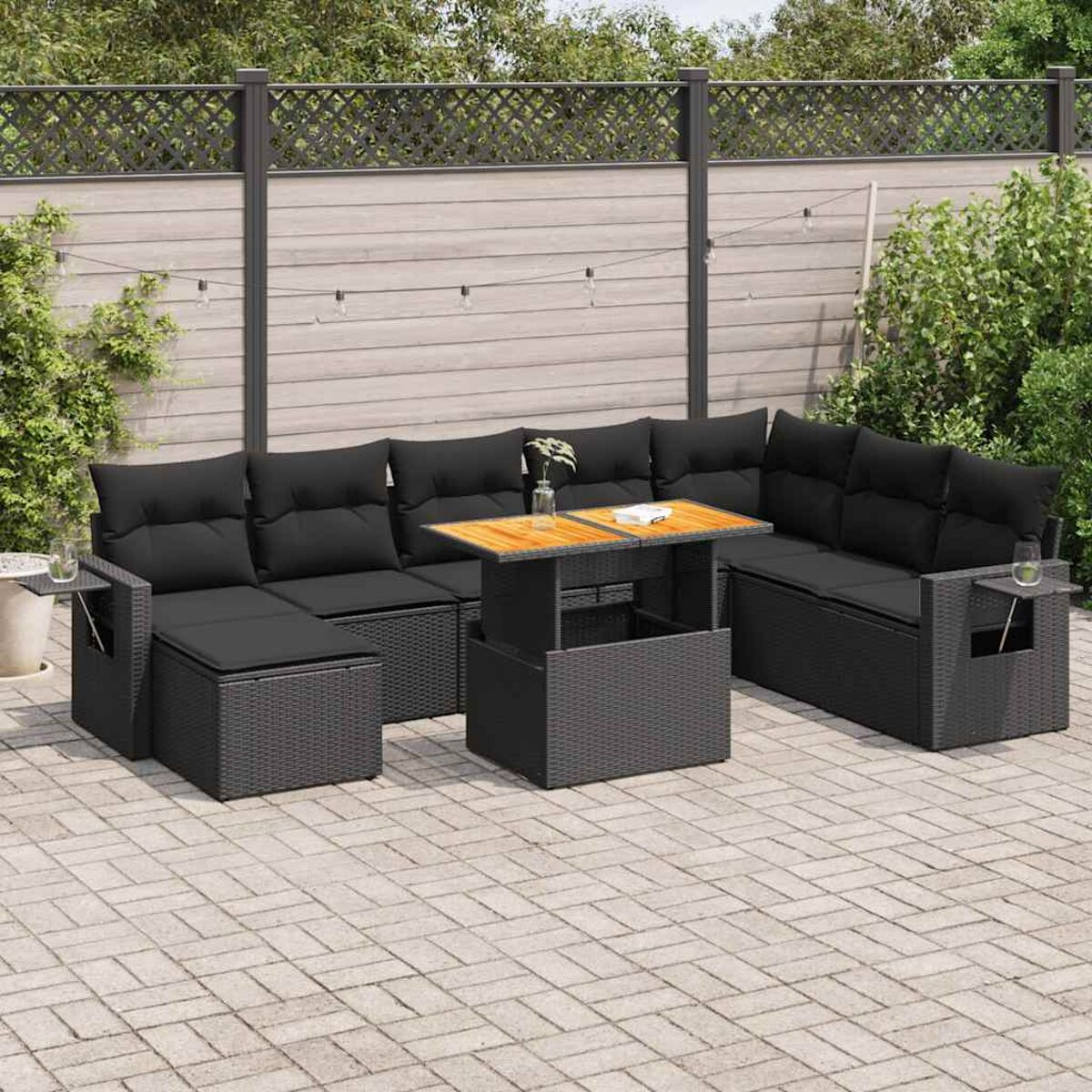Set di mobili da esterno. Stile rattan nero. Include sedute, un tavolo e cuscini. Sfondo neutro.