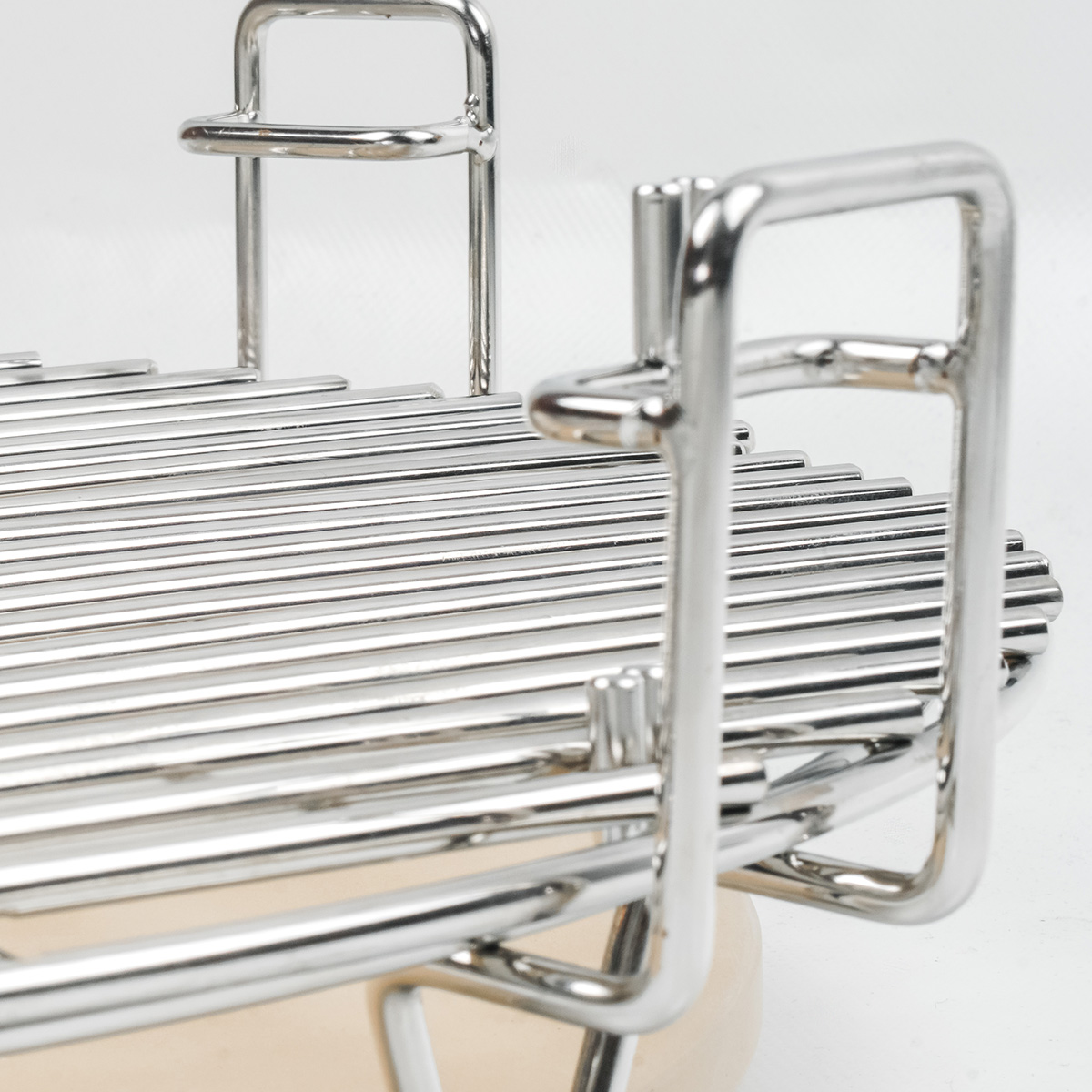 Close-up of stainless steel grill grates and handles. The grates are set on a wooden base.