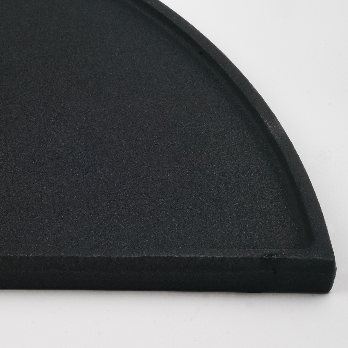Black, semi-circular object, curved edge. Close-up against a white background.