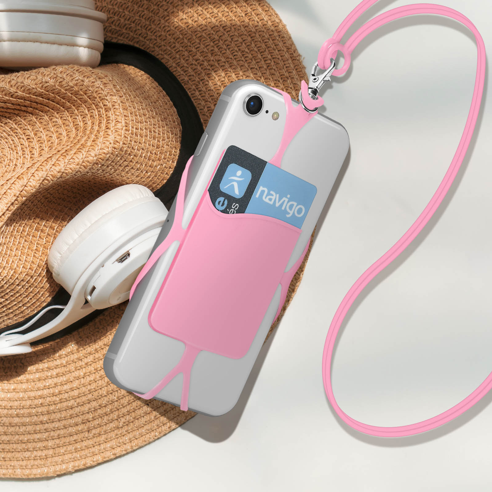 Custodia trasparente per telefono con cinturino rosa e porta carte, cuffie bianche e un cappello.