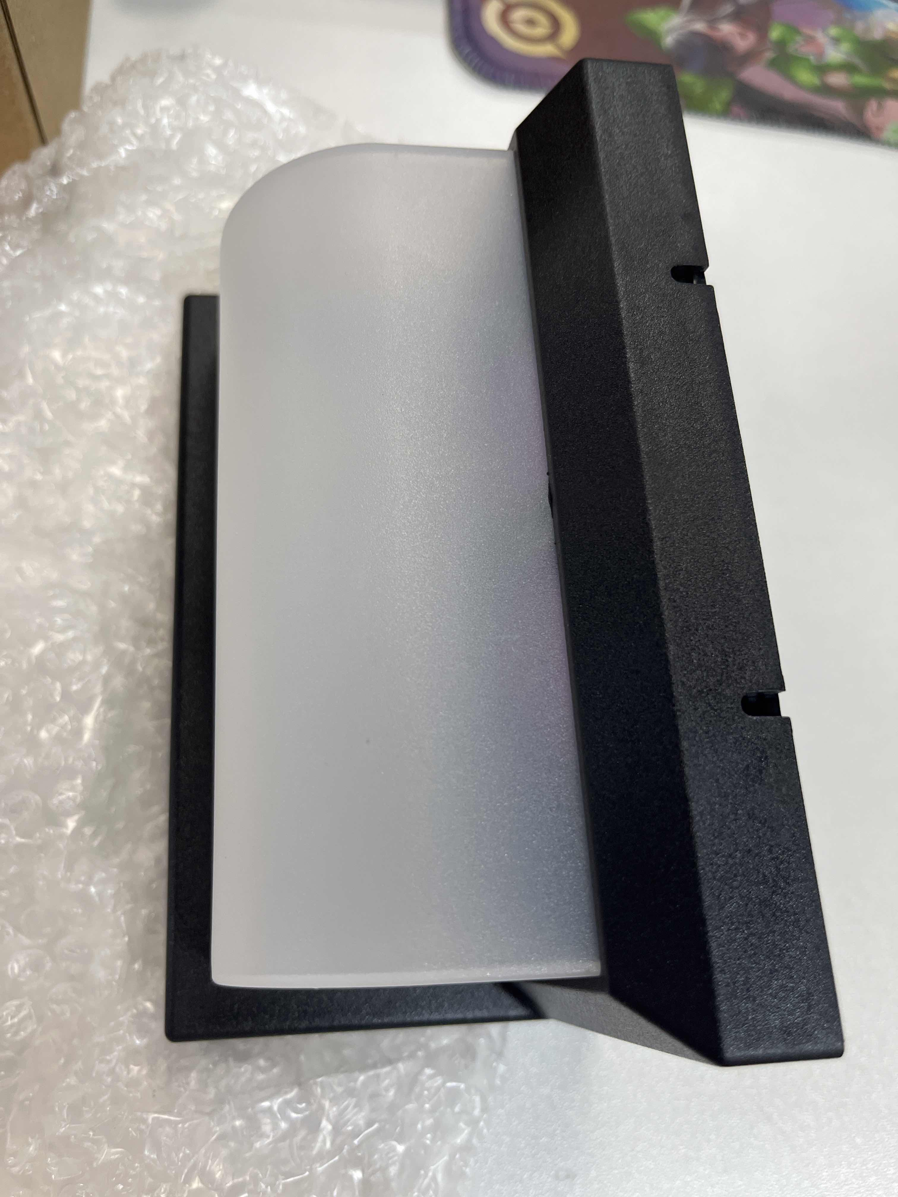 Schwarze Wandleuchte mit einem Schirm aus Milchglas vor weißem Hintergrund.