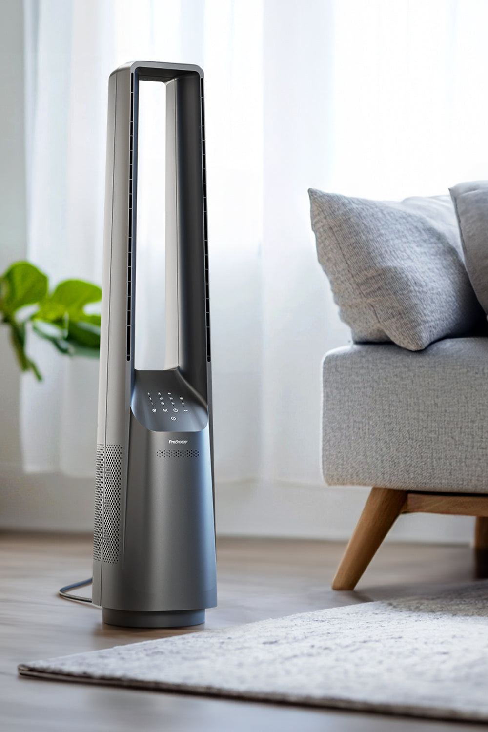 Hoher, dunkelgrauer Turmventilator in einem Raum. Sofa und Pflanze sichtbar, helle Beleuchtung.