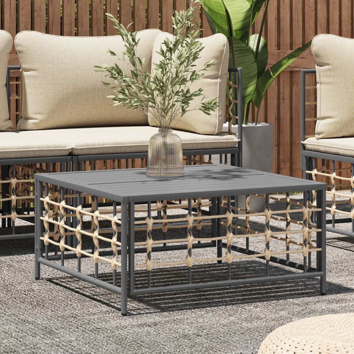 Grauer quadratischer Couchtisch mit gewebten Seitenteilen. Eine Terrasse mit Möbeln.