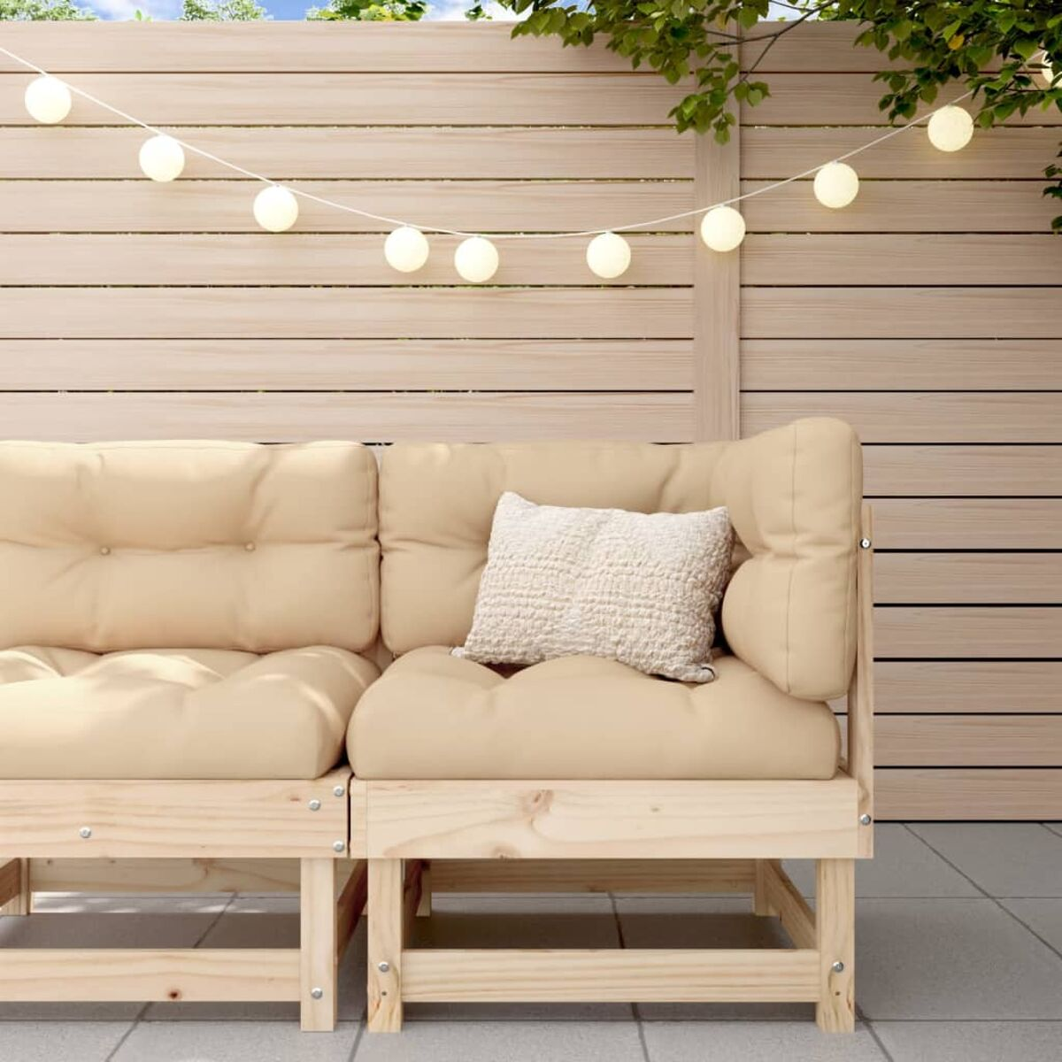 Holzsofa mit cremefarbenen Kissen und einem kleinen Kissen. Lichterkette an der Wand.