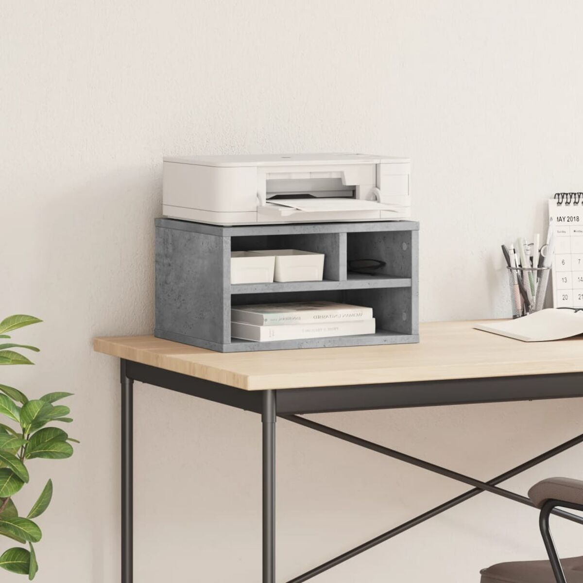 Schreibtisch-Organizer mit Drucker, kleinen Behältern und Büchern. Helle Holzoberfläche. Weiße Wand.